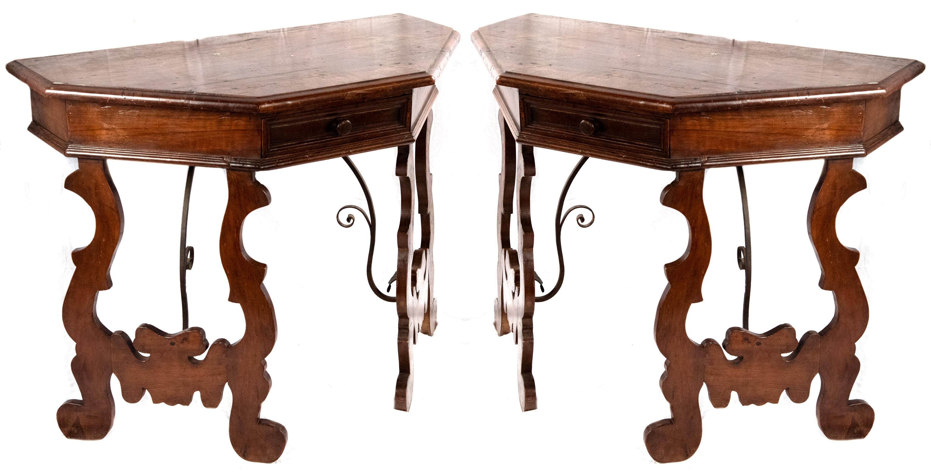 A pair of 18th century Spanish oak console tables, the top with a beveled edge above an unadorned apron fitted with a single small drawer with brass pull, raised on carved c-scroll trestle legs that are supported by scrolling metal braces.