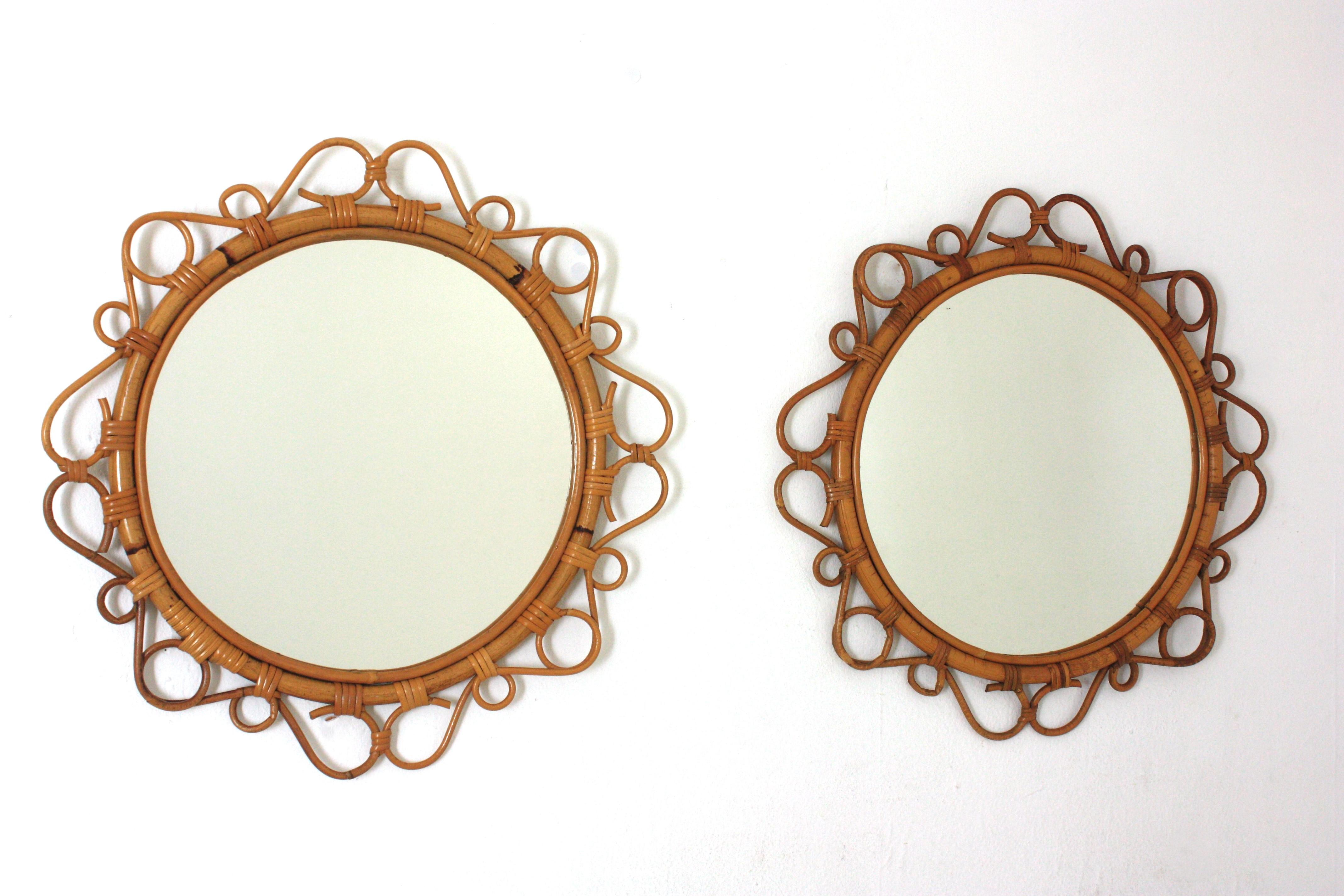 Coppia di specchi in bambù e rattan realizzati a mano con dettagli a volute che circondano la cornice, Spagna, anni Sessanta. 
Questi specchi da parete mediterranei presentano una cornice circolare in bambù circondata da decorazioni a volute e