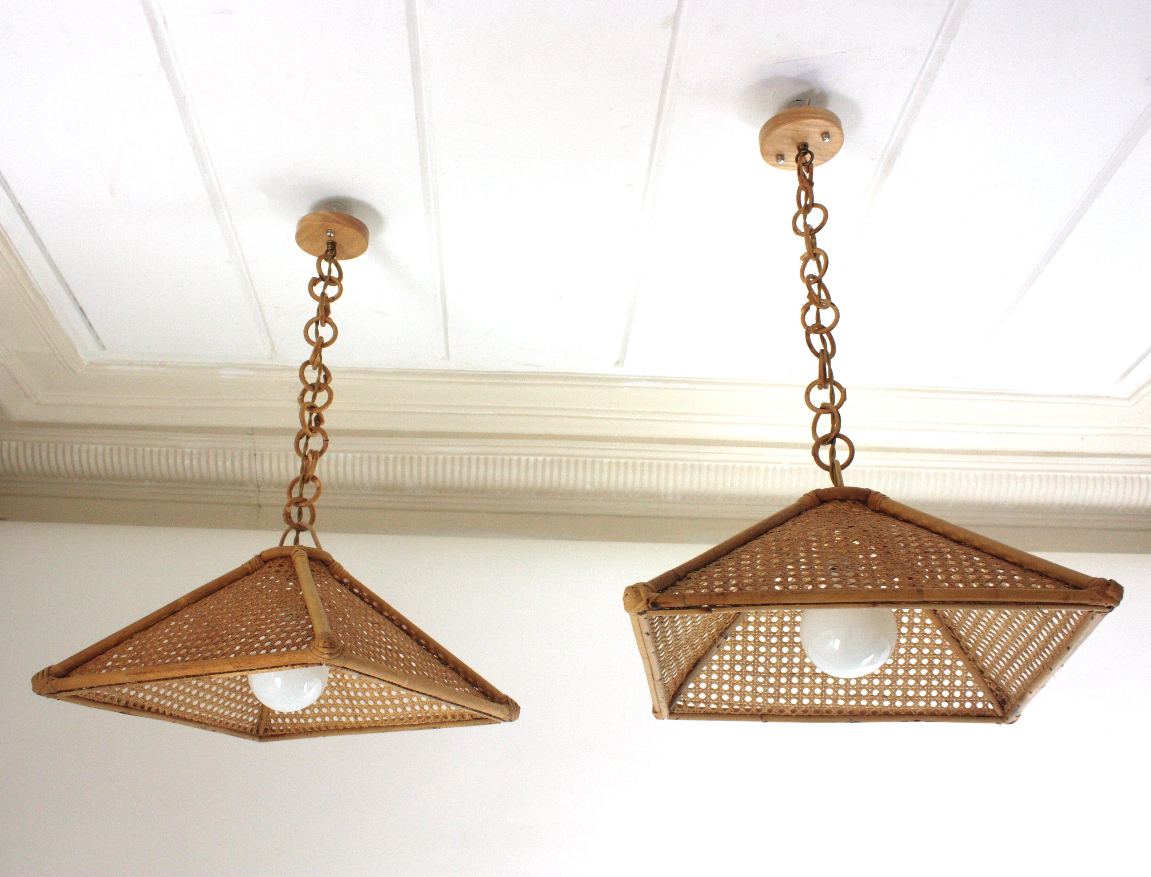 Coppia di pendenti / lampadari a forma trapezoidale in filo di vimini e rattan di stile Mid-Century Modern. Spagna, anni '60
Questa coppia di lampade a sospensione presenta una struttura trapezoidale in rattan con pannelli in filo di vimini appesi a