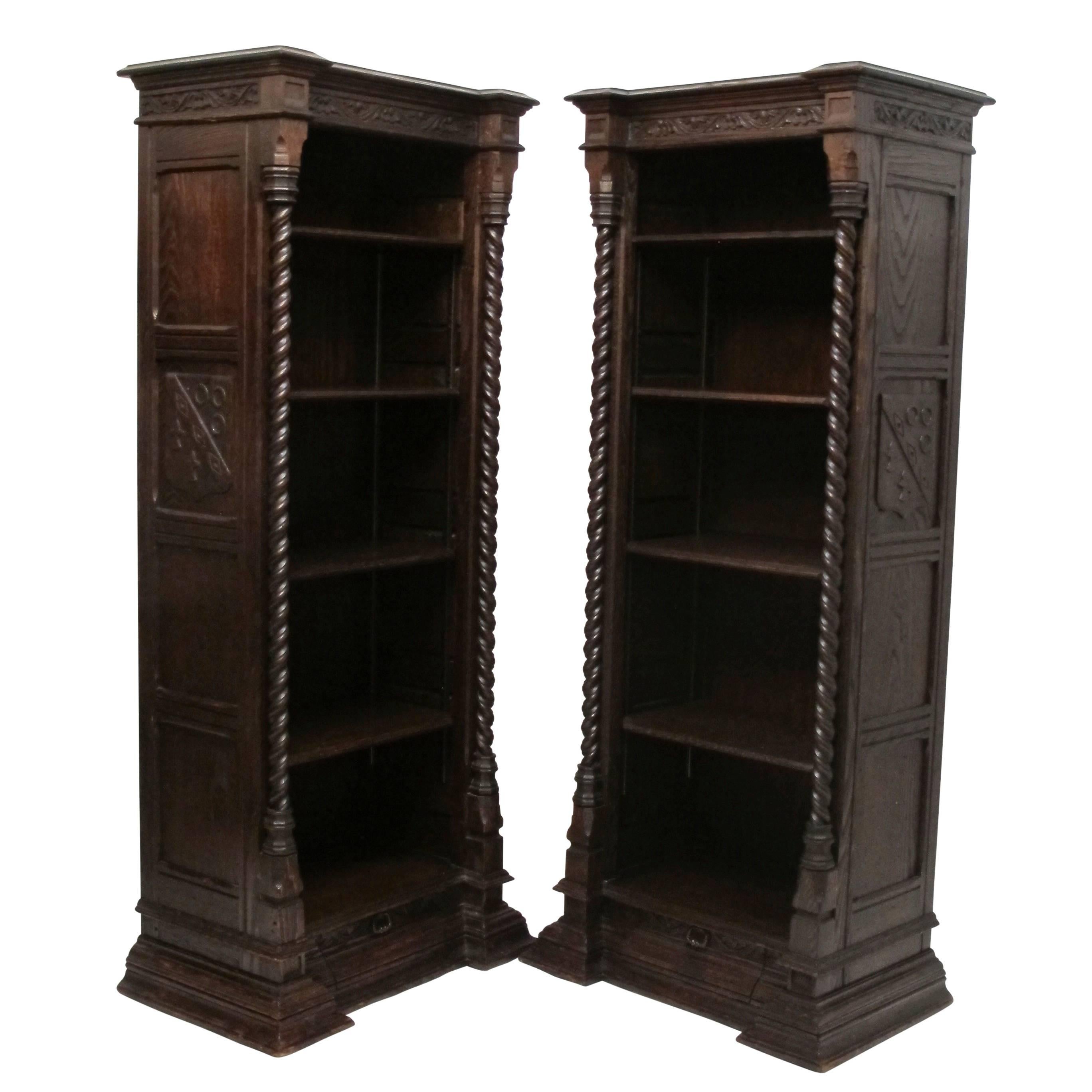 A pair of solid oak Spanish Revival bookcases with four adjustable shelves. Having a single drawer in the base of the moulding, shelves flanked by a pair of twisted columns, and with carved sides and carving around the top apron. American, first