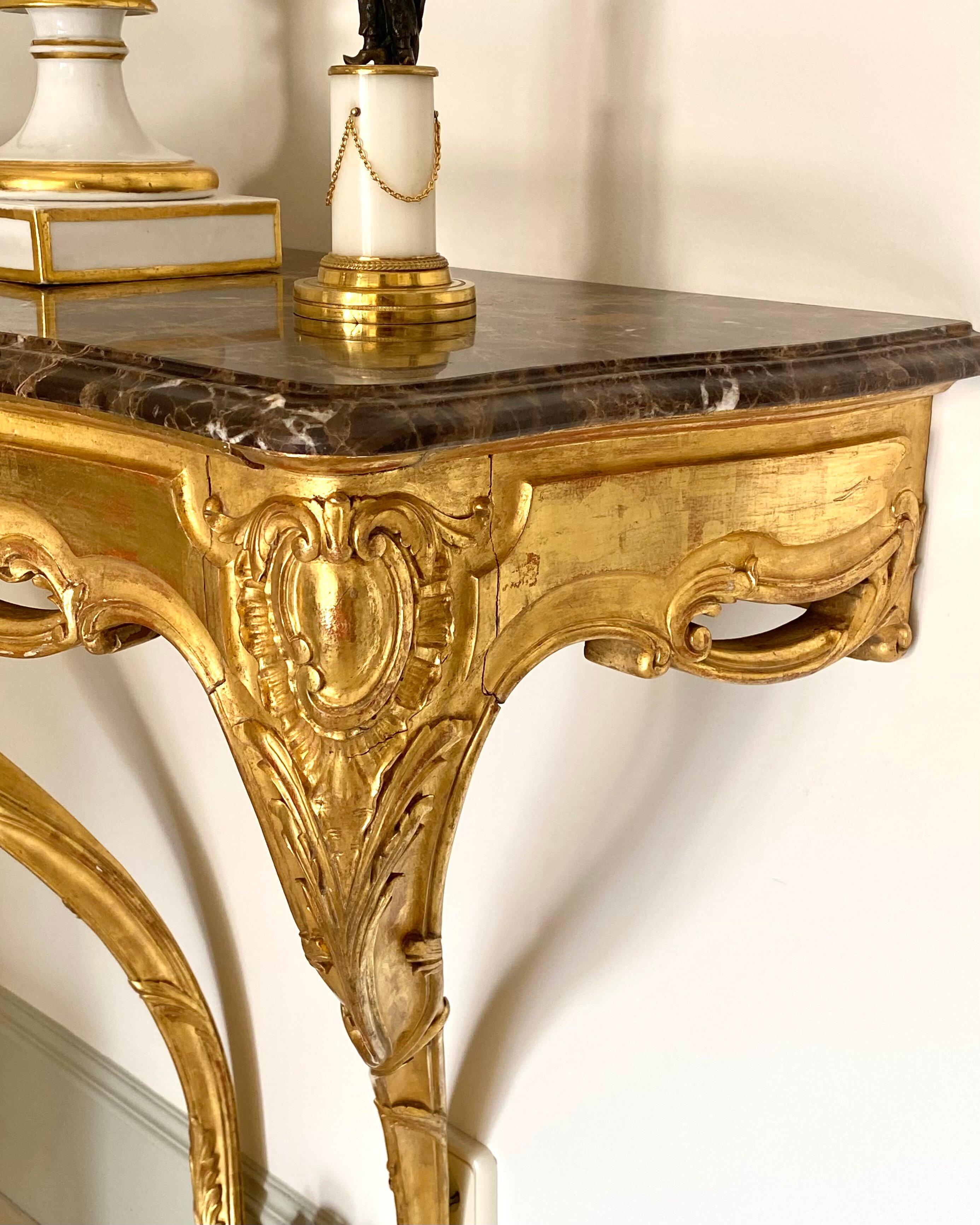 Pair of Spanish 19th century console tables in the Rococo - Louis XV style or Carlos III (king of Spain between 1759 and 1788) style.
Made of hand-carved gilded wood with traditional rococo decoration of garlands of flowers and foliage as well as