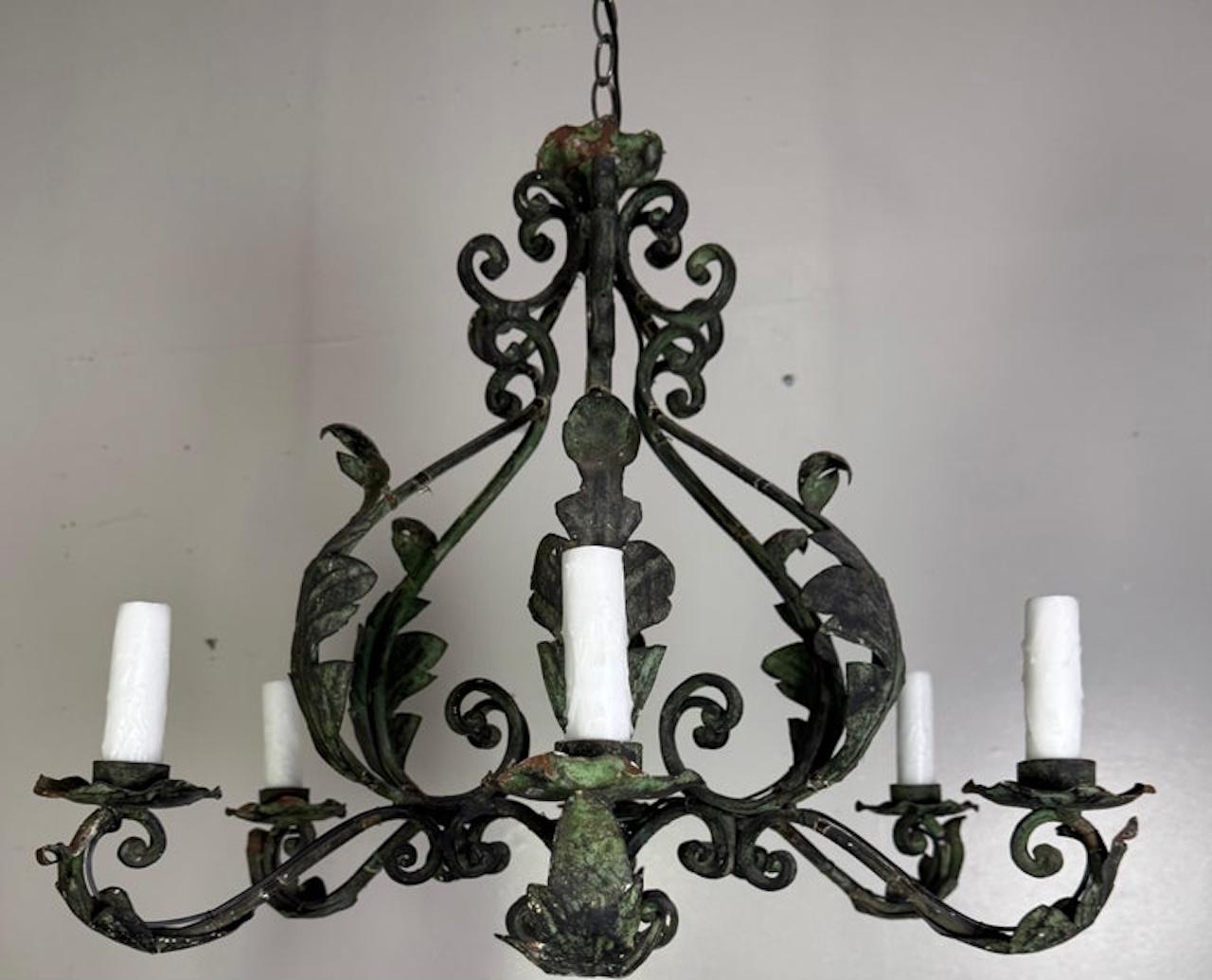This exquisite pair of six-light wrought iron chandeliers captures the timeless grandeur of Spanish decorative lighting. Their elegant, openwork frames are adorned with deeply scrolled arms and intricate foliate detailing, evoking the Baroque and