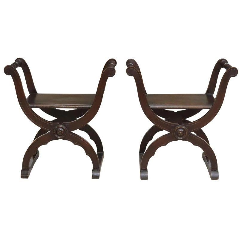 A pair of Spanish Renaissance style classic X shape wood curule stools with scrolled turned arms, and a circular motif detail.