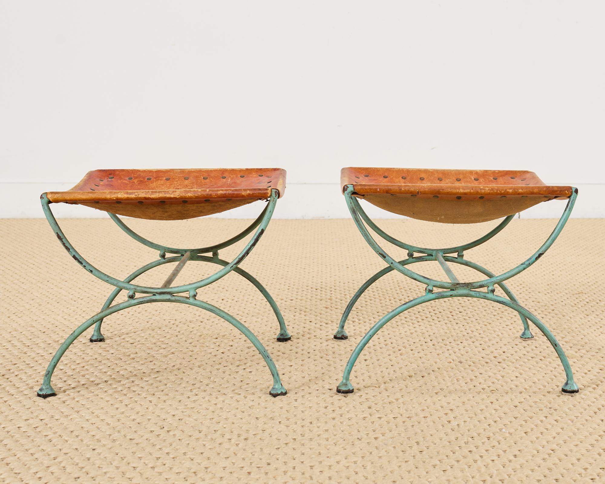 Magnifique paire de tabourets ou bancs en fer forgé de style moderne du milieu du siècle, avec des pieds curules de style gréco-romain. Fabriqué en fer forgé massif avec une patine vieillie et une finition vert-de-gris. Le design de style espagnol