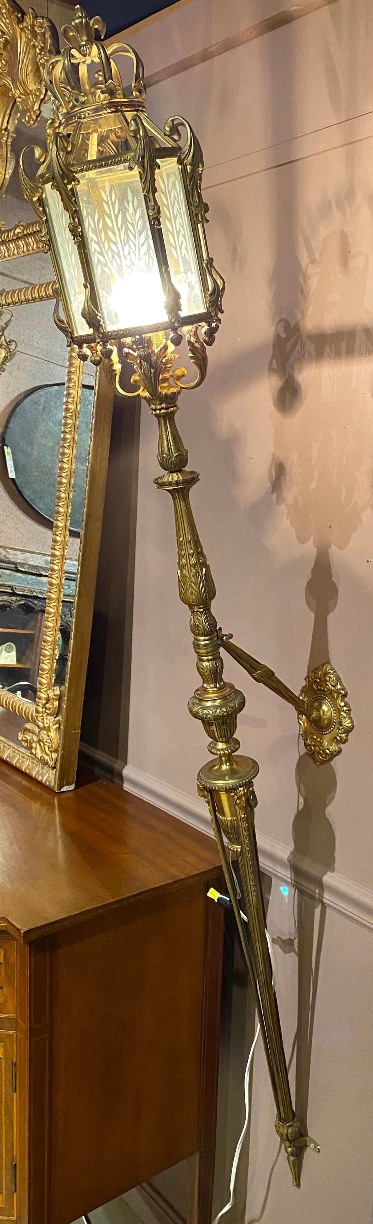 A fine pair of Spanish wall mounted scroll decorated brass single light torchieres with etched glass panels, decorative brass stems, wall mounts and base supports. This pair date to the early 20th century in very good working condition, with minor