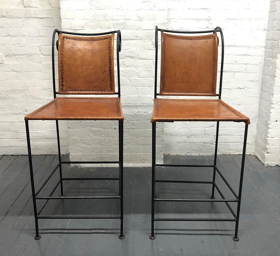 Pair of Spanish wrought iron and leather barstools. The stools have handstitched rawhide seats and backs with wrought iron scrolled back.