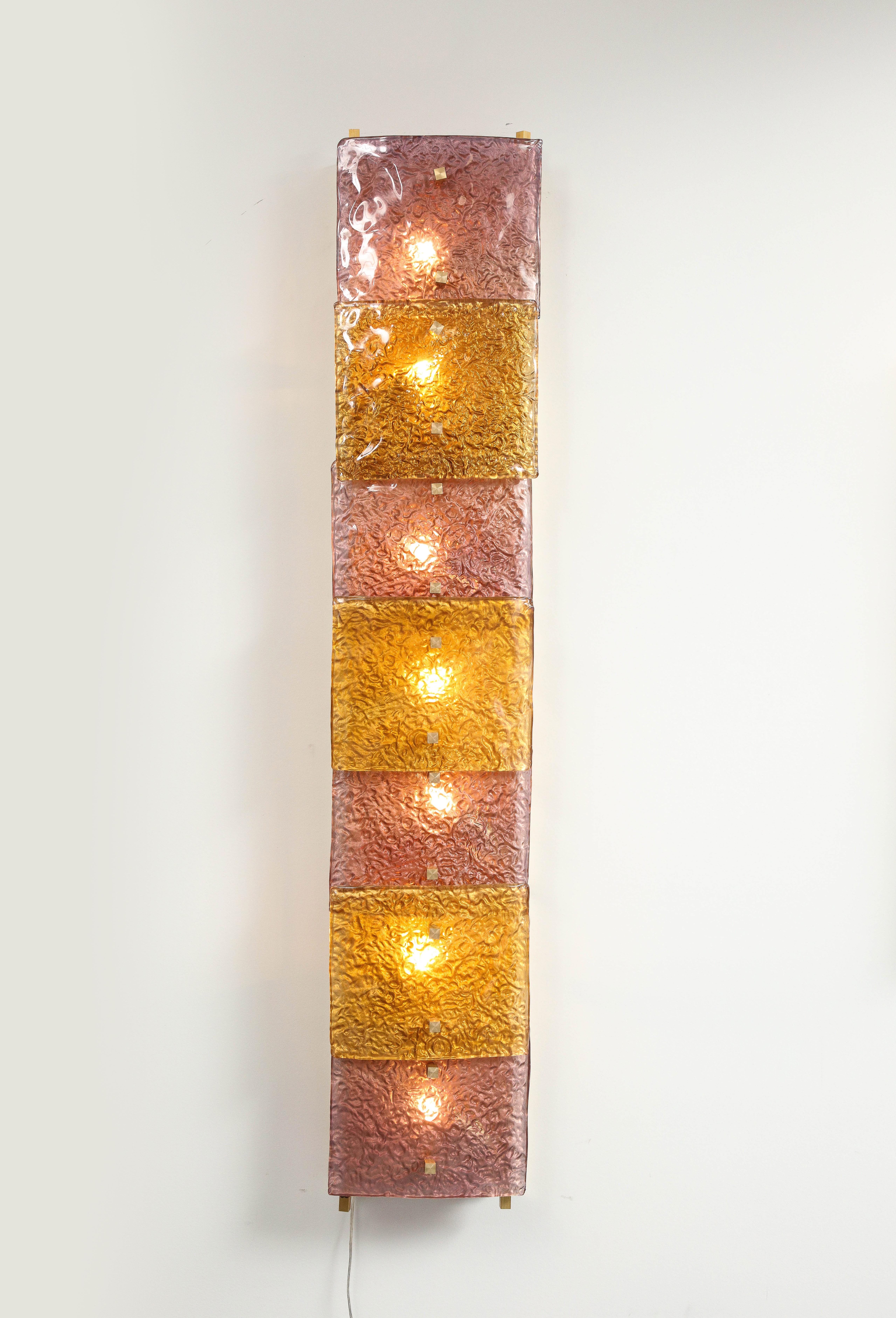 This pair of sconces is impressive for its scale. The variation of colors is warm. There are made with an assemblage of Murano glasses. Each one has seven lights.The structure and support of each sconce is a brass plate elegantly designed. Both