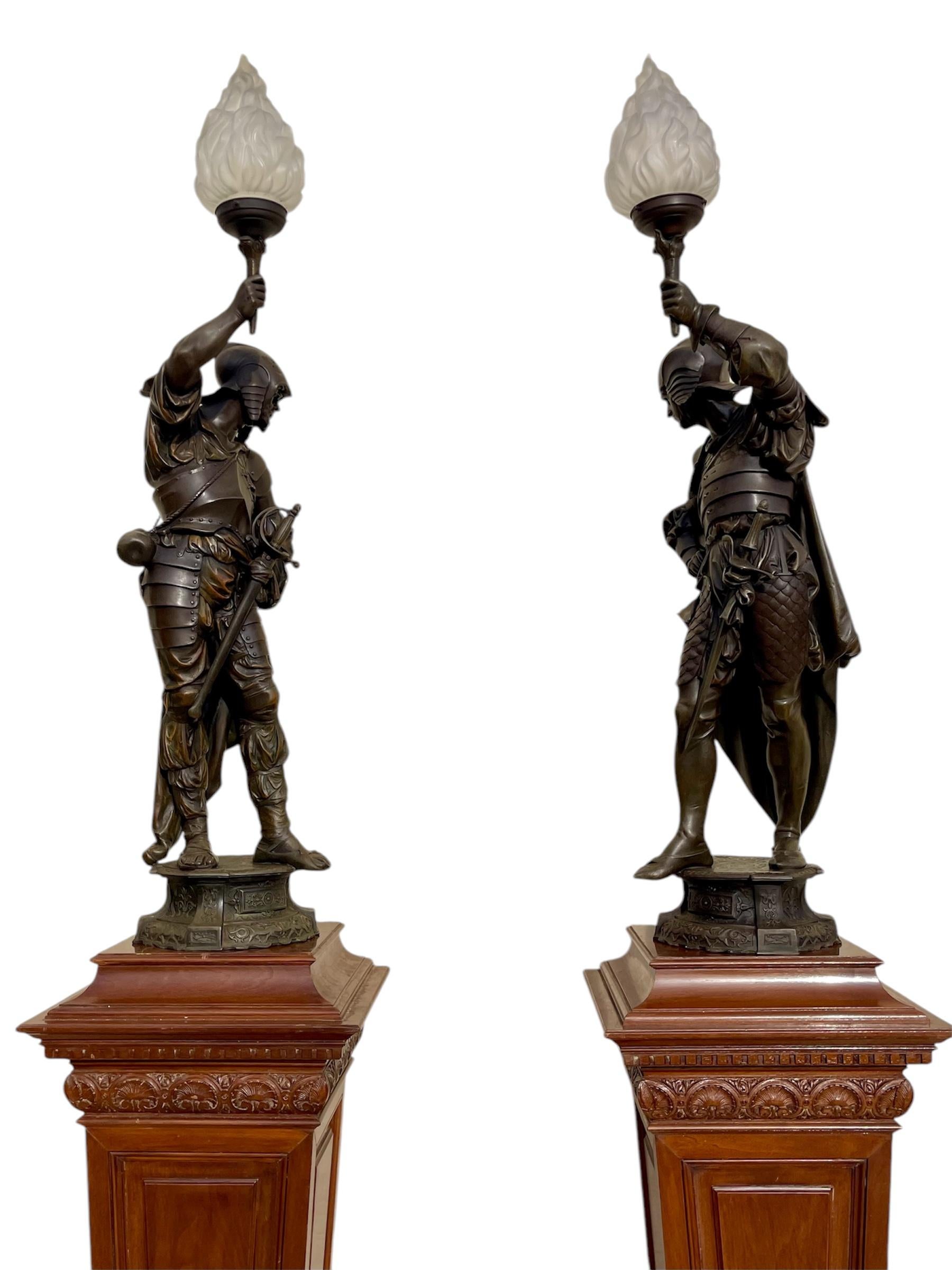 Paire de torchères / lampes en étain datant du début du 20e siècle. Chacune représente un chevalier médiéval tenant une flamme de verre à la main. Ces lames sont électrifiées et fonctionnent.
 
 Dimensions
 Hauteur totale 1m30
 Hauteur sans globes