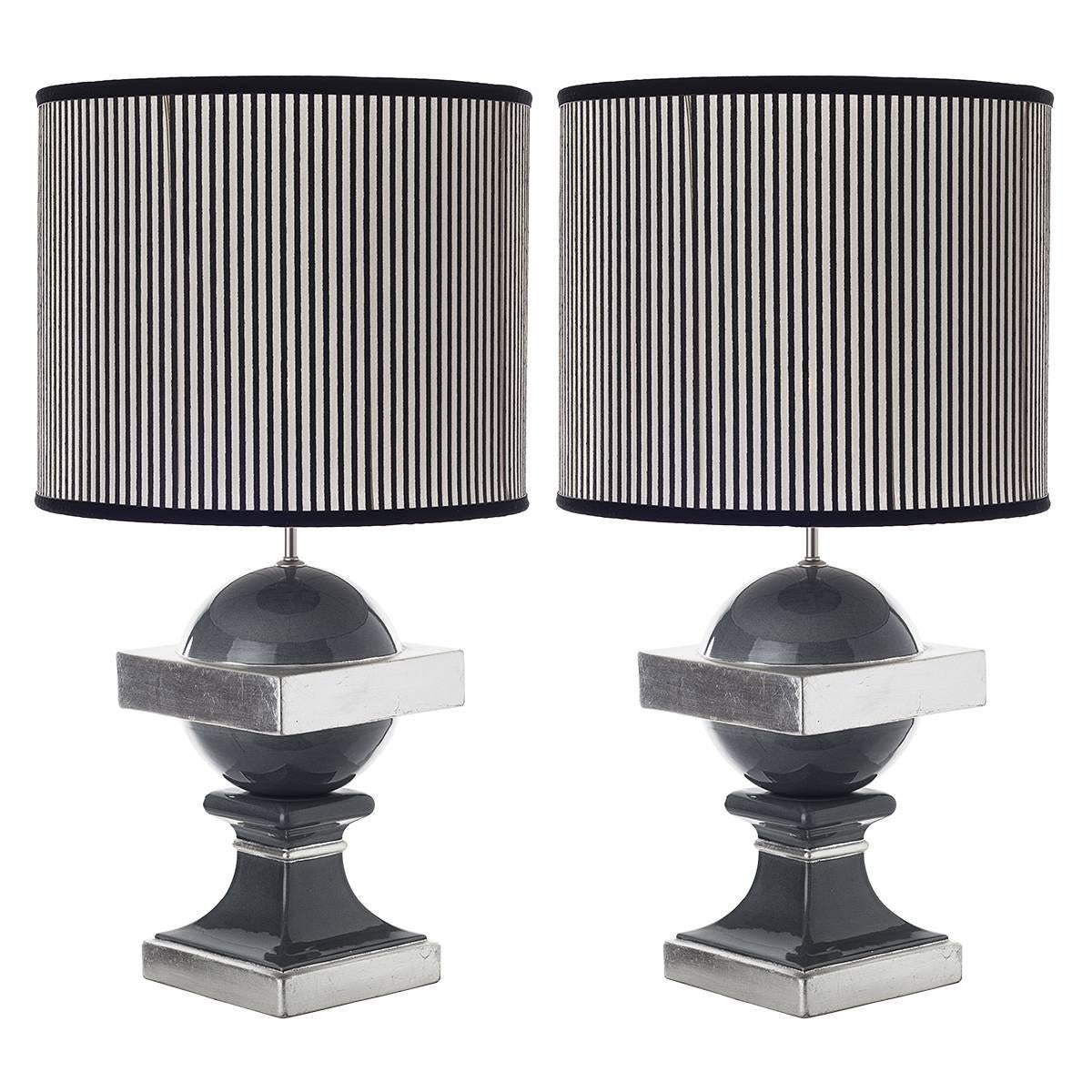 Pair of spherical transitional ceramic table lamps with shades.
These transitional table lamps show a contemporary finish, a crackle charcoal grey enriched by silver leaf details, on a more traditional lamp. The shades are lined, in a geometric,