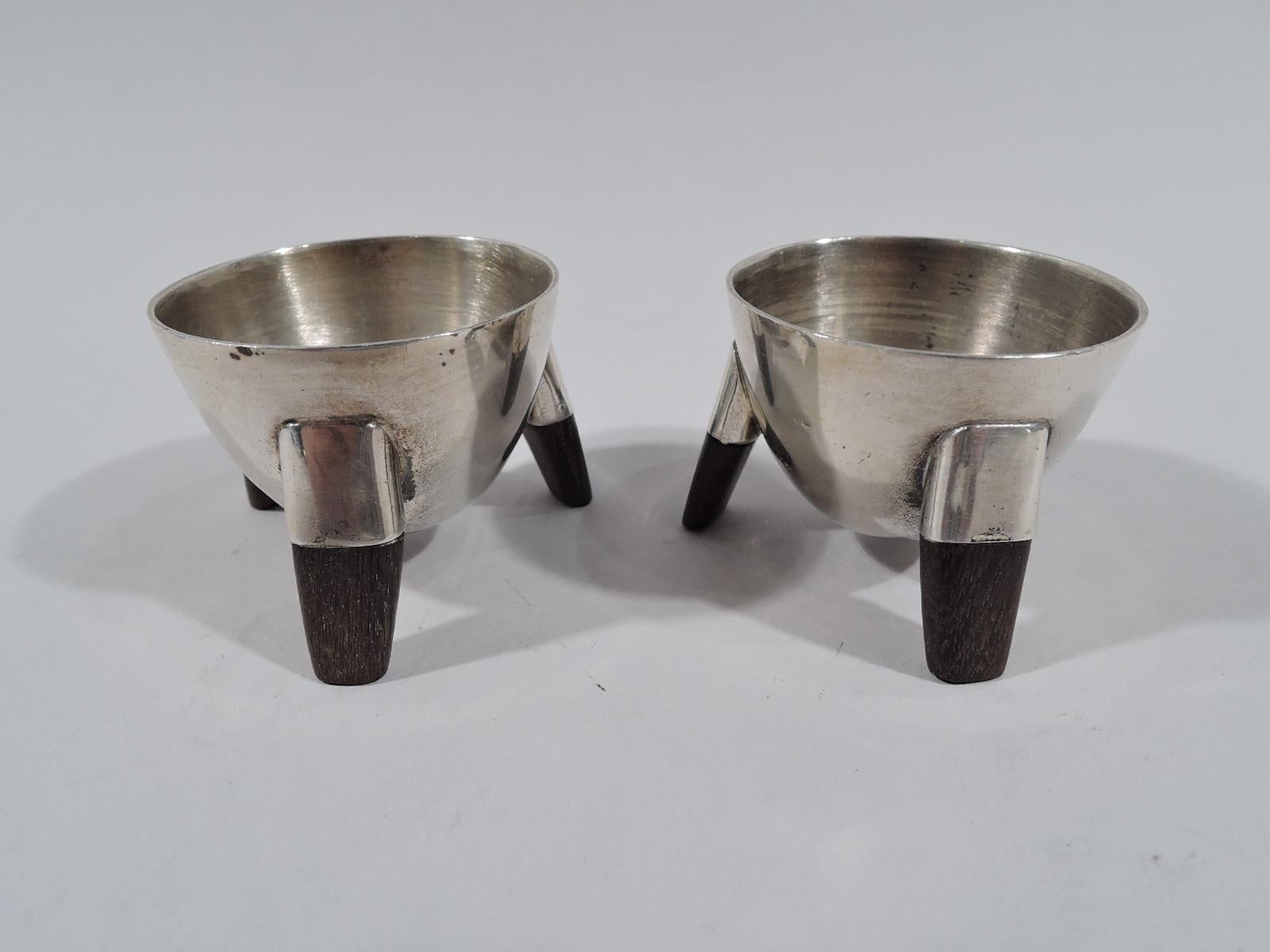 Pair of Mid-Century Modern sterling silver open salts. Made by Spratling in Taxco, Mexico. Conical bowl with 3 side-mounted stained-wood peg supports. Fully marked with maker’s stamp (circa 1964-1967) and eagle stamp with no. 30. Total gross weight: