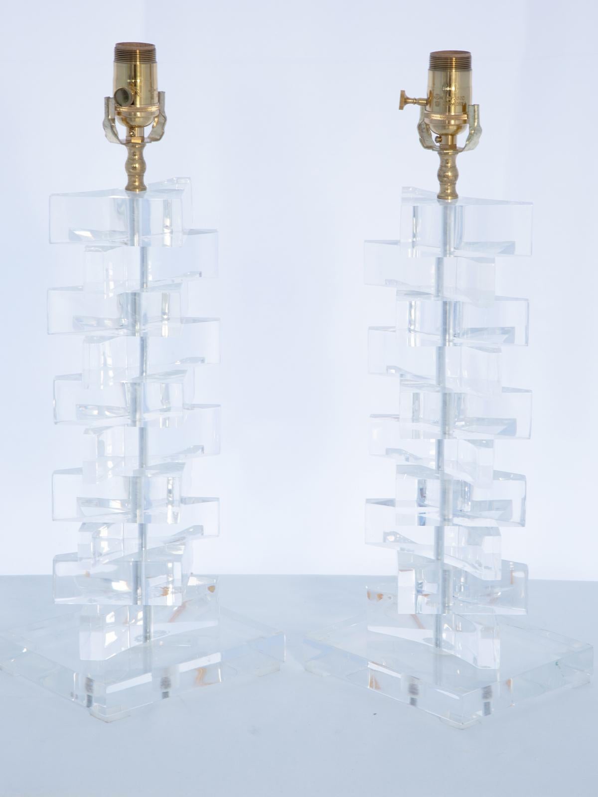 Pair of vintage lamps, of Lucite, in the style of Karl Springer. Each newly rewired lamp is a stack of triangular blocks atop a rectangular base. 

Stock ID: D4029