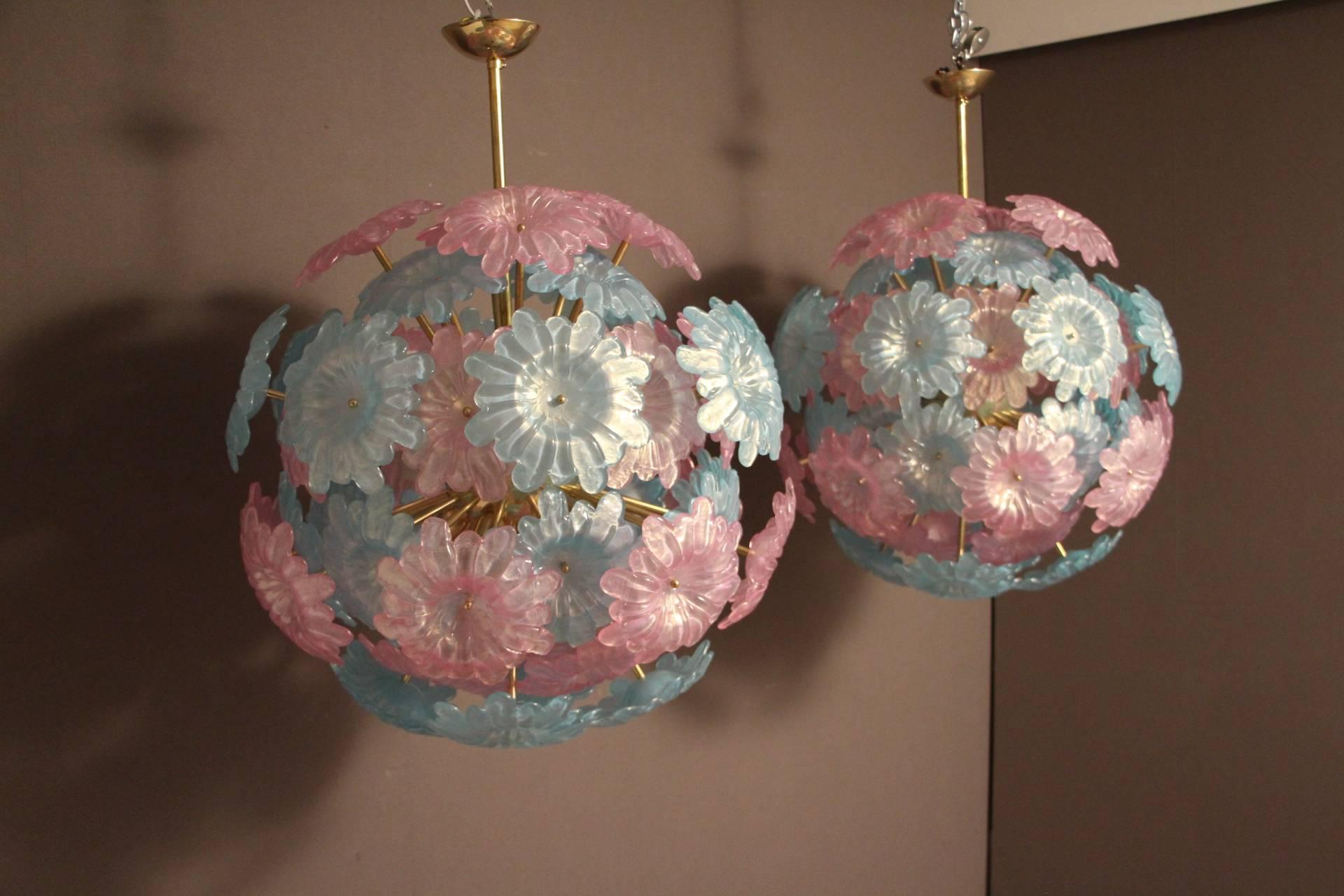 Very chic pair of chandeliers featuring brass rods ending with large flat Murano glass blue and pink flowers. These flowers have a delicate pearly color.
When the light is on, they make a lot of reflects on ceiling and walls. It is superb!
They