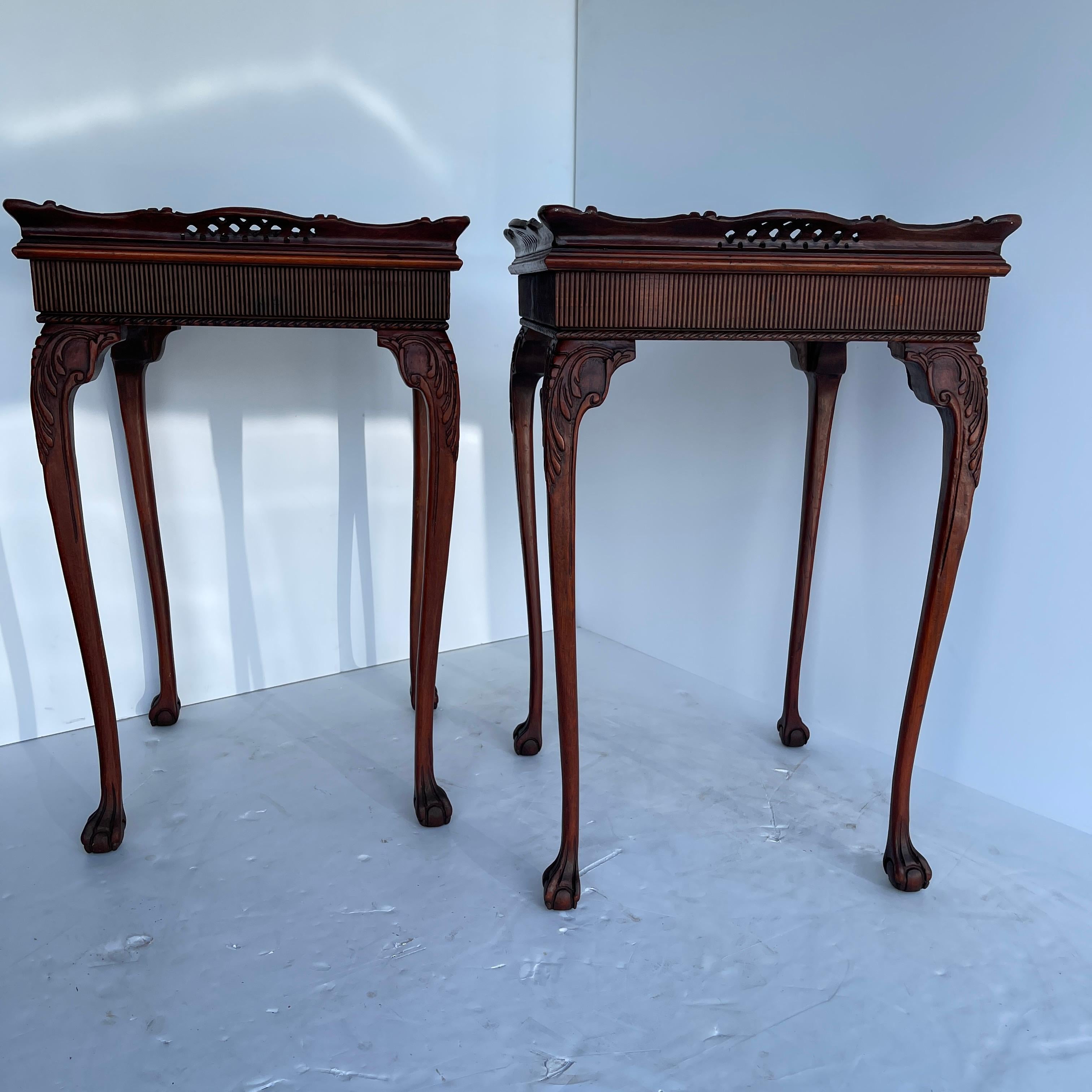 Two late 19th century Chinese Chippendale side tables. This ornately carved pair of tables are graceful with long curved legs and ball and claw carved feet. Beautifully restored, the mahogany wood has a warm rich glow. The carved sides along the top