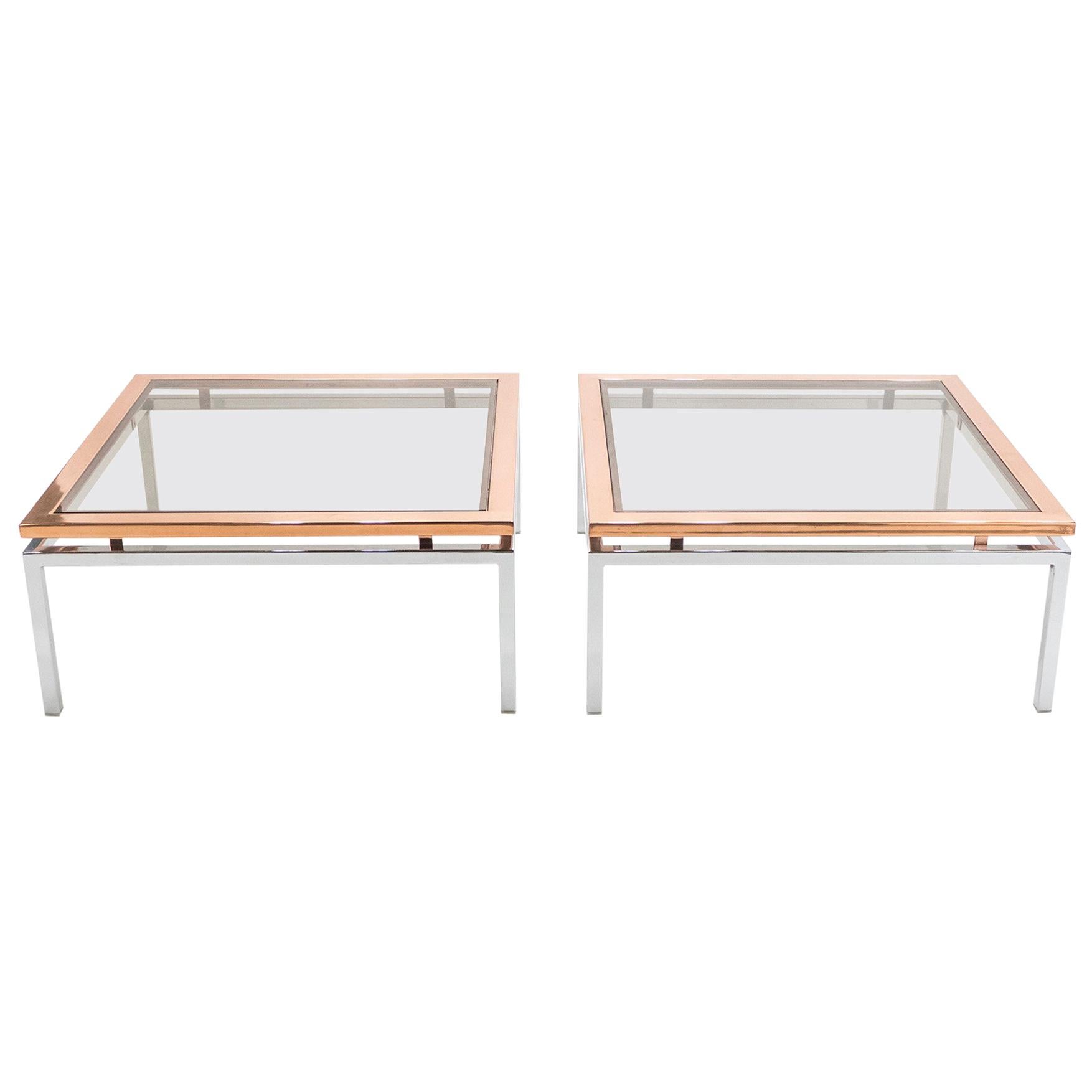 Simple lines and shiny metal point to this pair of coffee tables French Hollywood Regency roots. Designed by Guy Lefevre for Maison Jansen, it features chrome legs and with a large copper frame top covered by a lightly smoked glass. Its symmetry,