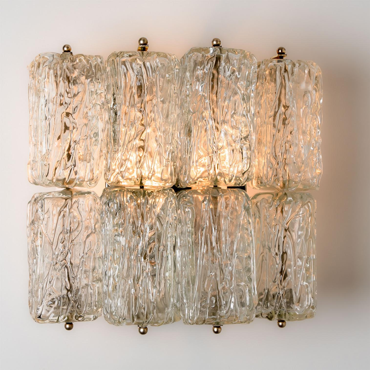 Beautiful high quality light fixture made by Kalmar, Austria. Manufactured in mid century, circa 1970 (at the end of 1960s and beginning of 1970s).

This wall light features lights made of handmade textured glass and white back plate. The sides