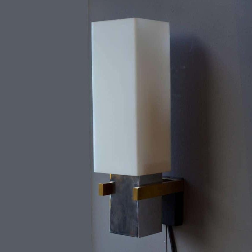 Wall lights consisting of opaline glass square shades with chrome lamp holders are connected with black metal and brass brackets. Their minimal and compact design is made with maximal combination of materials used in Italian lighting of the 1960's.