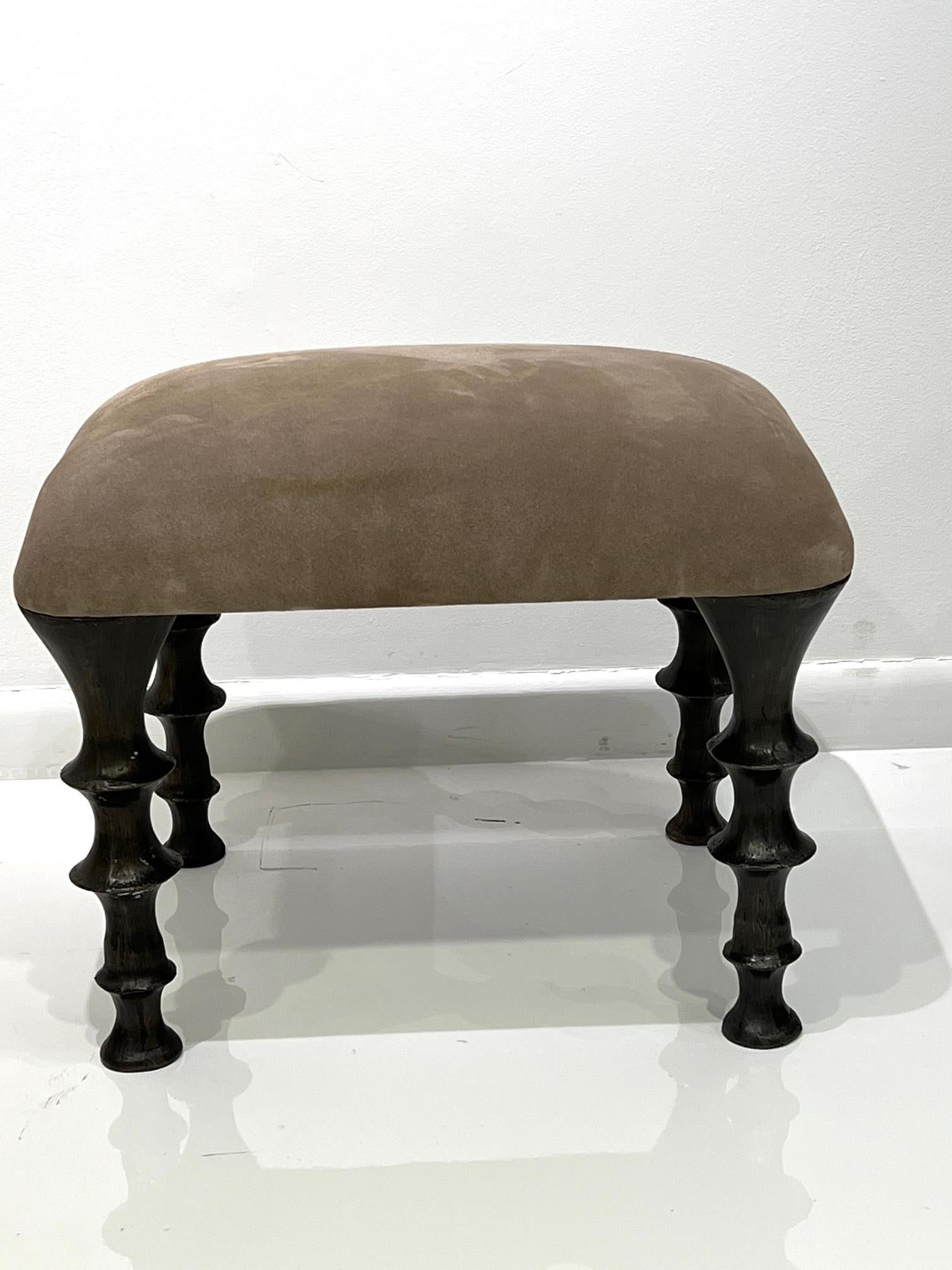 Two stools with cast bronze legs and a brown suede cushions. The design of the legs have an organic texture. These stools will make a powerful statement in your interior. Stools can also be made custom in different size and upholstery. (COM).