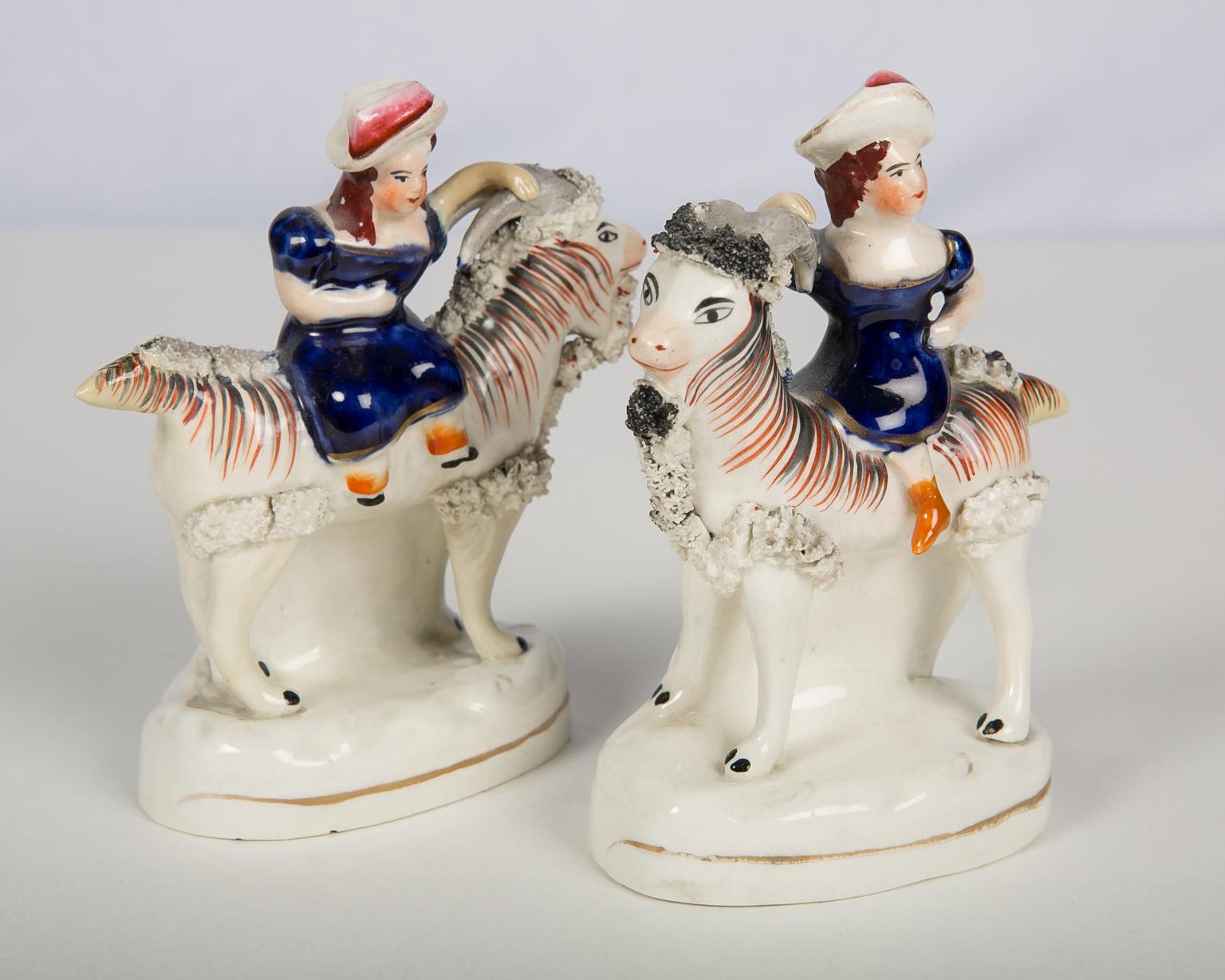 We are pleased to offer this pair of adorable Staffordshire figures of children, each riding a goat. The charming figures are 
painted with enamels of cobalt blue, pink and orange. Made circa 1880, the bases are oval shaped with a thin gold line