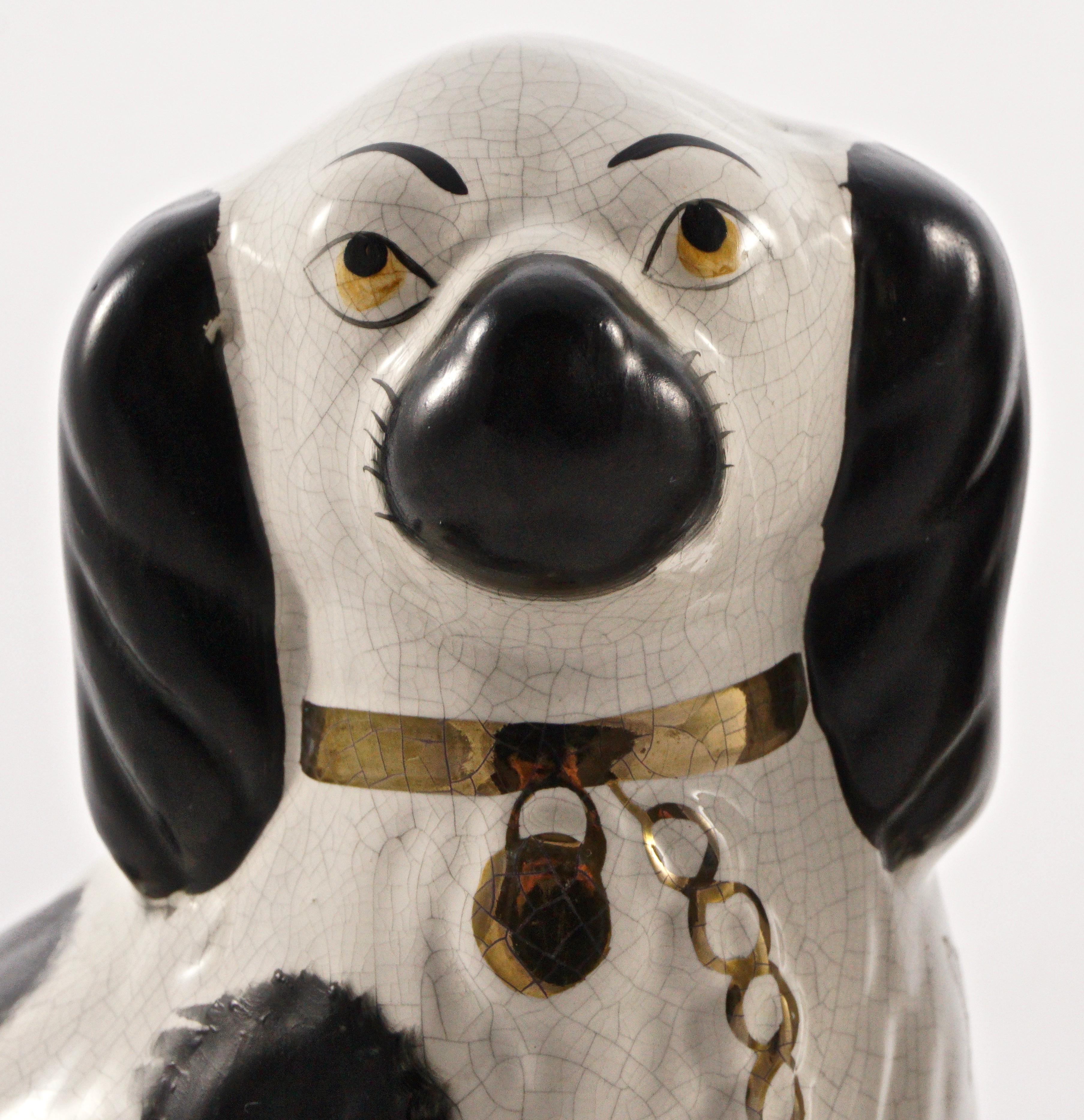 Pair of classic Staffordshire pottery hand painted black and white dogs decorated with gold accents, circa early twentieth century. They measure approximately height 21.8cm / 8.58 inches by width at the base 17.3cm / 6.8 inches, and have typical