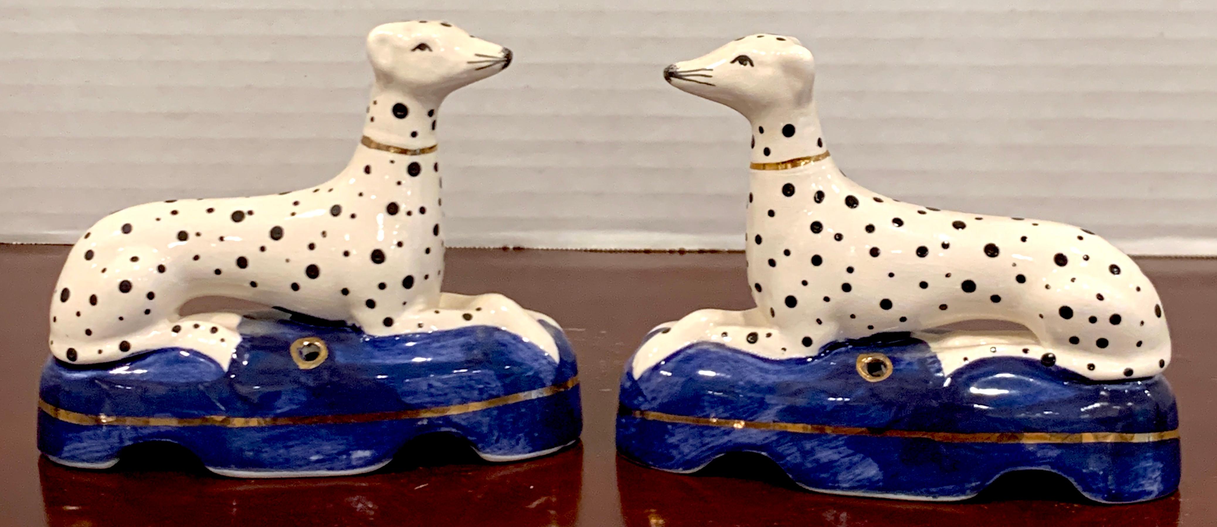 Pair of Staffordshire seated Dalmatian inkwells, each one reclining with front legs crossed, resting on an oval blue cushion. Unmarked, later 19th century examples.

   