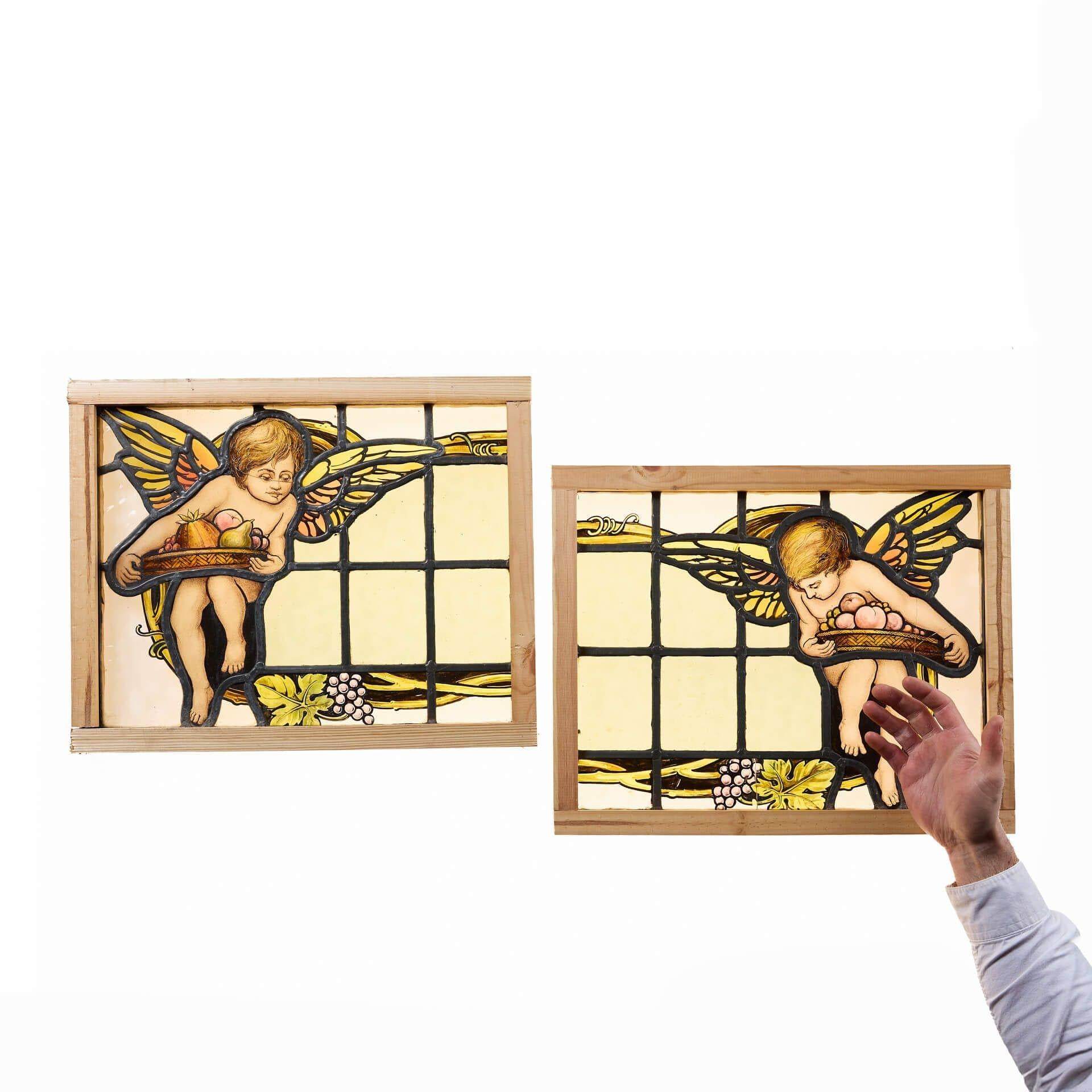 An elegant pair of English arts and crafts stained glass window panels dating to circa 1890.
 
To create scene of winged putto bearing platters of fruit with a green tinted centre bordered by stylised grape vines.
 
Though dating from the late 19th