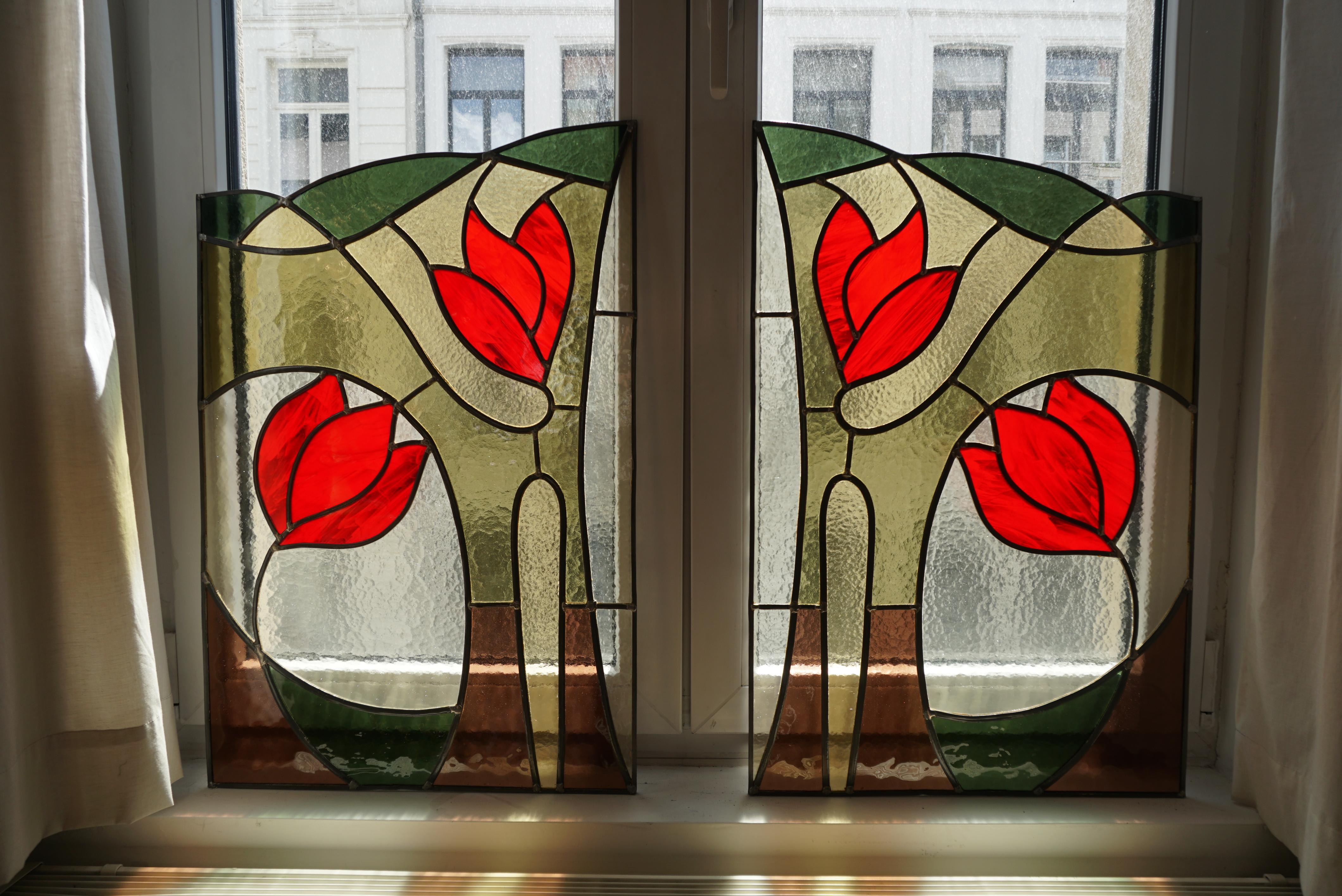 A pair of stained glass window panels from France, circa 1900- 1950. The red colors of these stained glass windows with tulips are said to come to life in the early morning sunshine.

Height 30.3