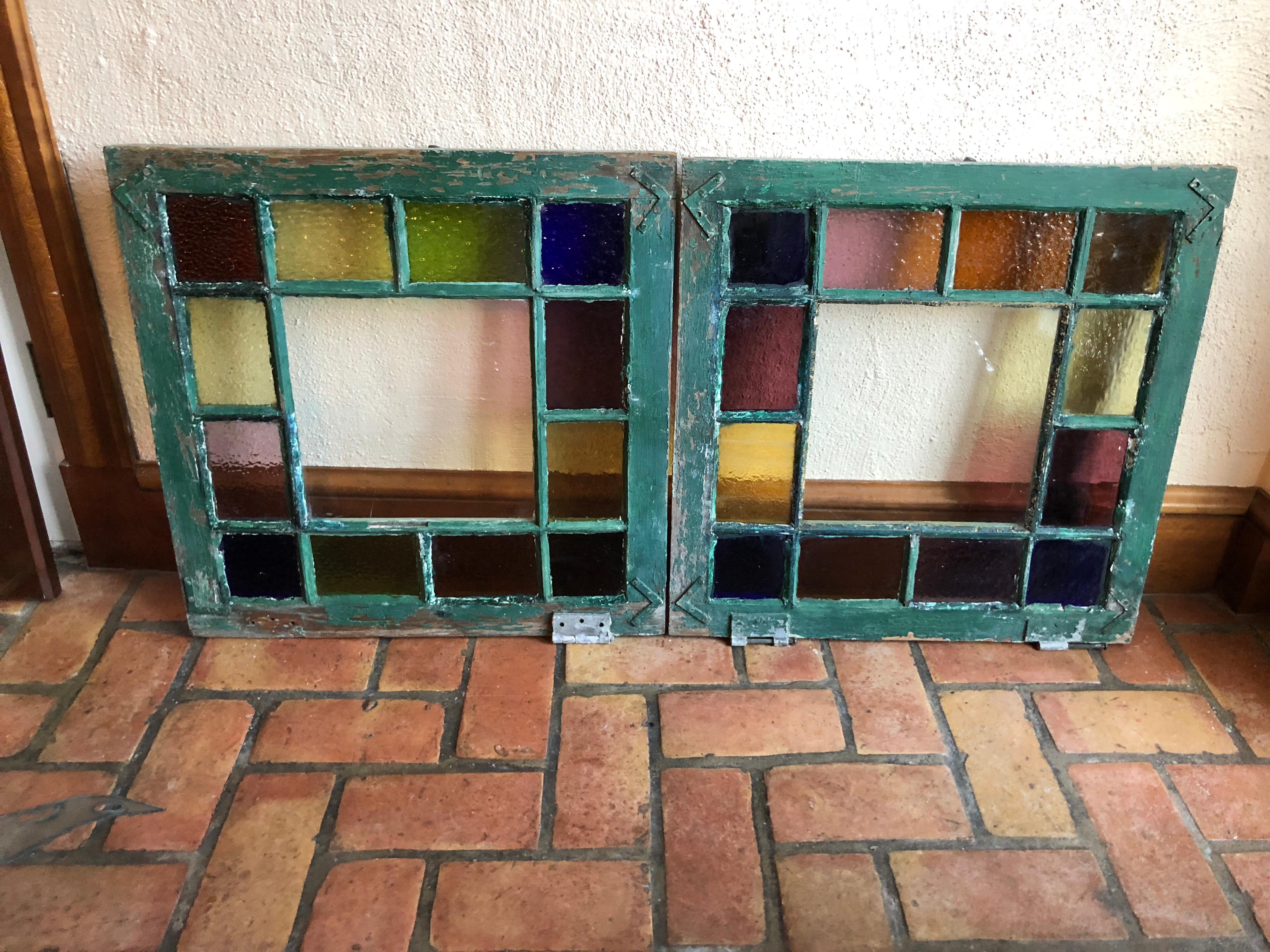 Pair of stained glass windows. Bright and colorful these would add to any interior or exterior project. The colors include cobalt blue , amber, yellow ,green and purple all around the edges. There is a large clear glass panel in the very center of