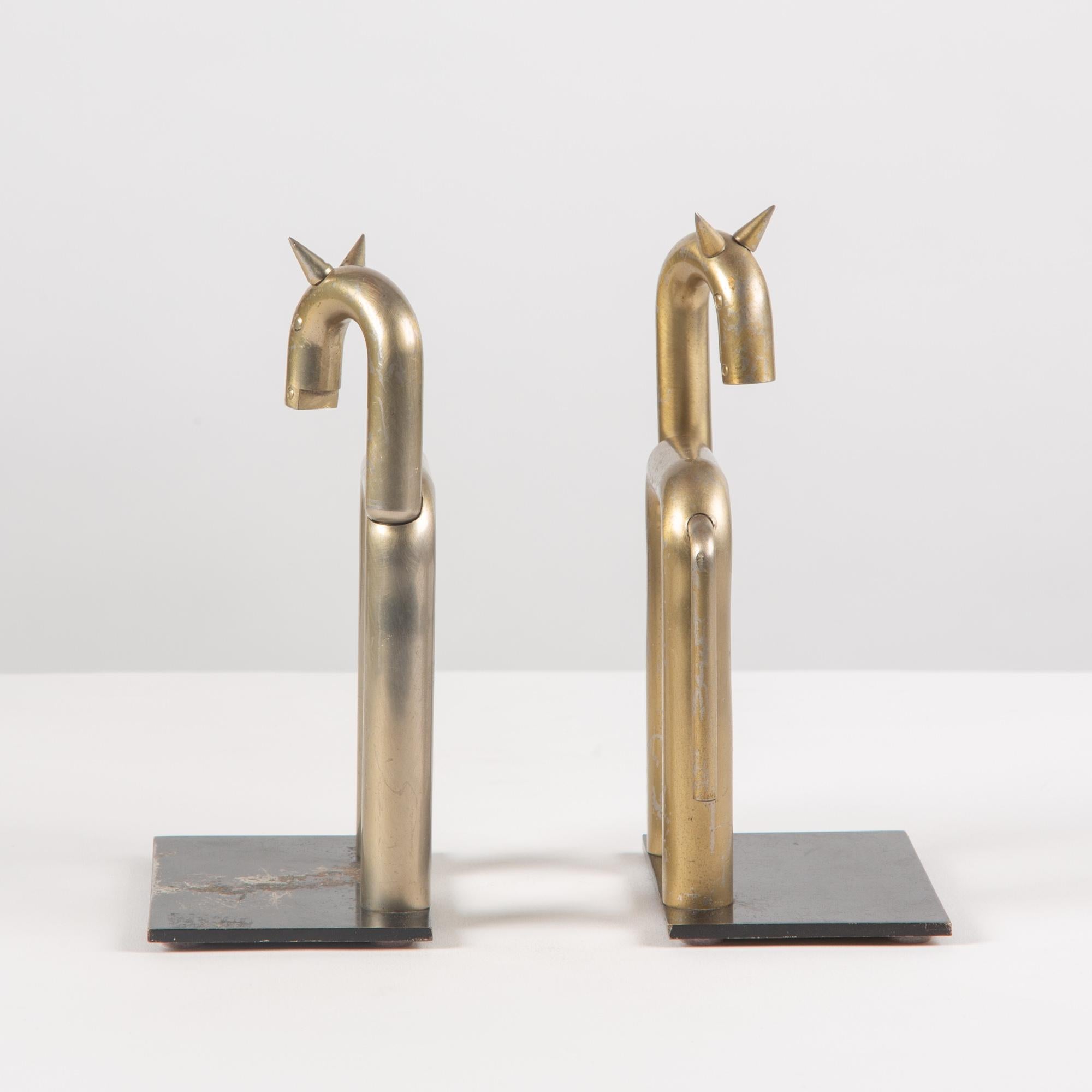 Pair of patinated stainless steel bookends by Walter von Nessen for Chase, c.1930s, USA. The pair of bookends feature a black painted metal base with geometric horse figures in a golden hue. This playful pair will liven any bookshelf.

The chase