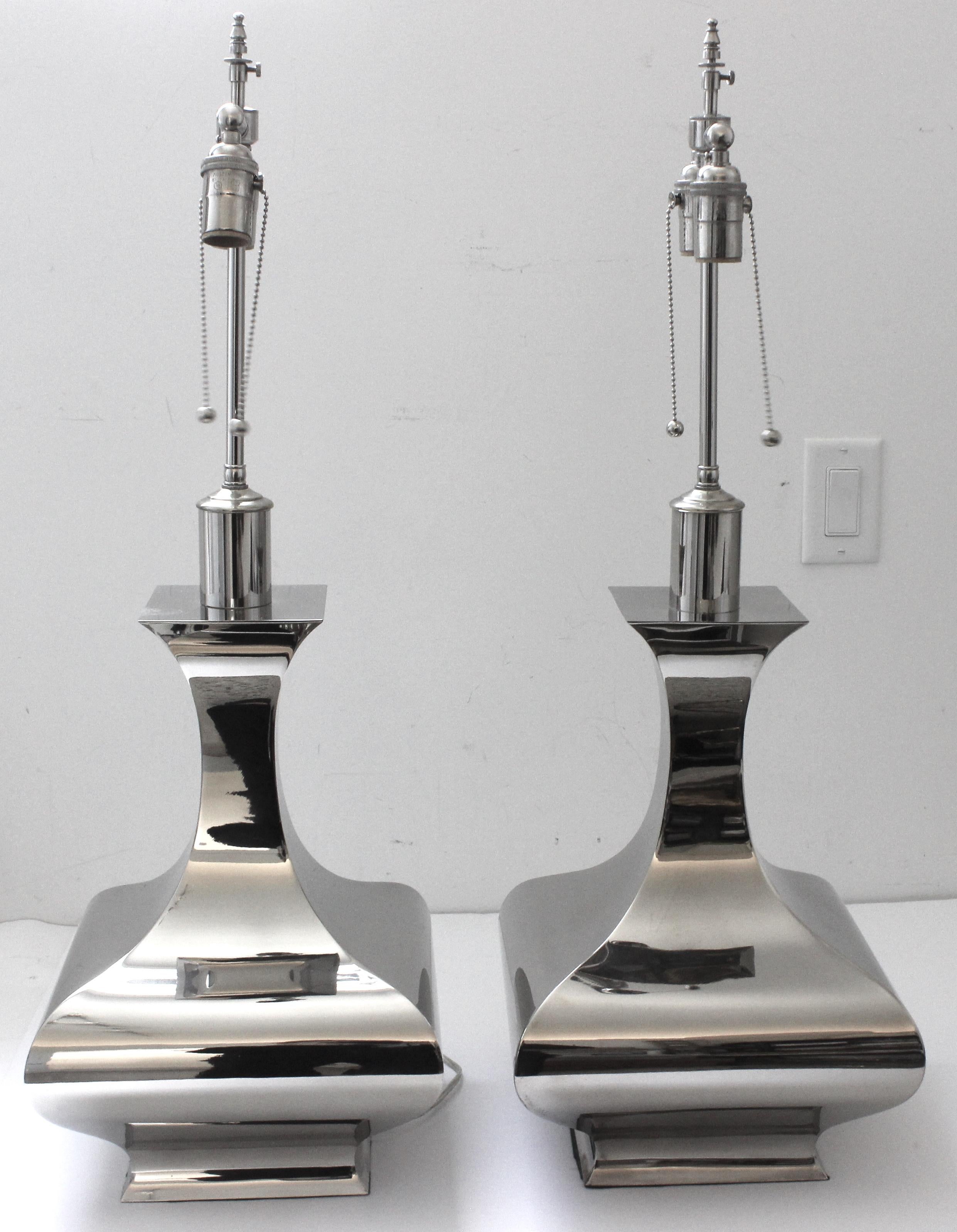 Cette paire de lampes de table en acier inoxydable, en forme de vase, est très proche des pièces créées par Tommi Parzinger et James Mont.