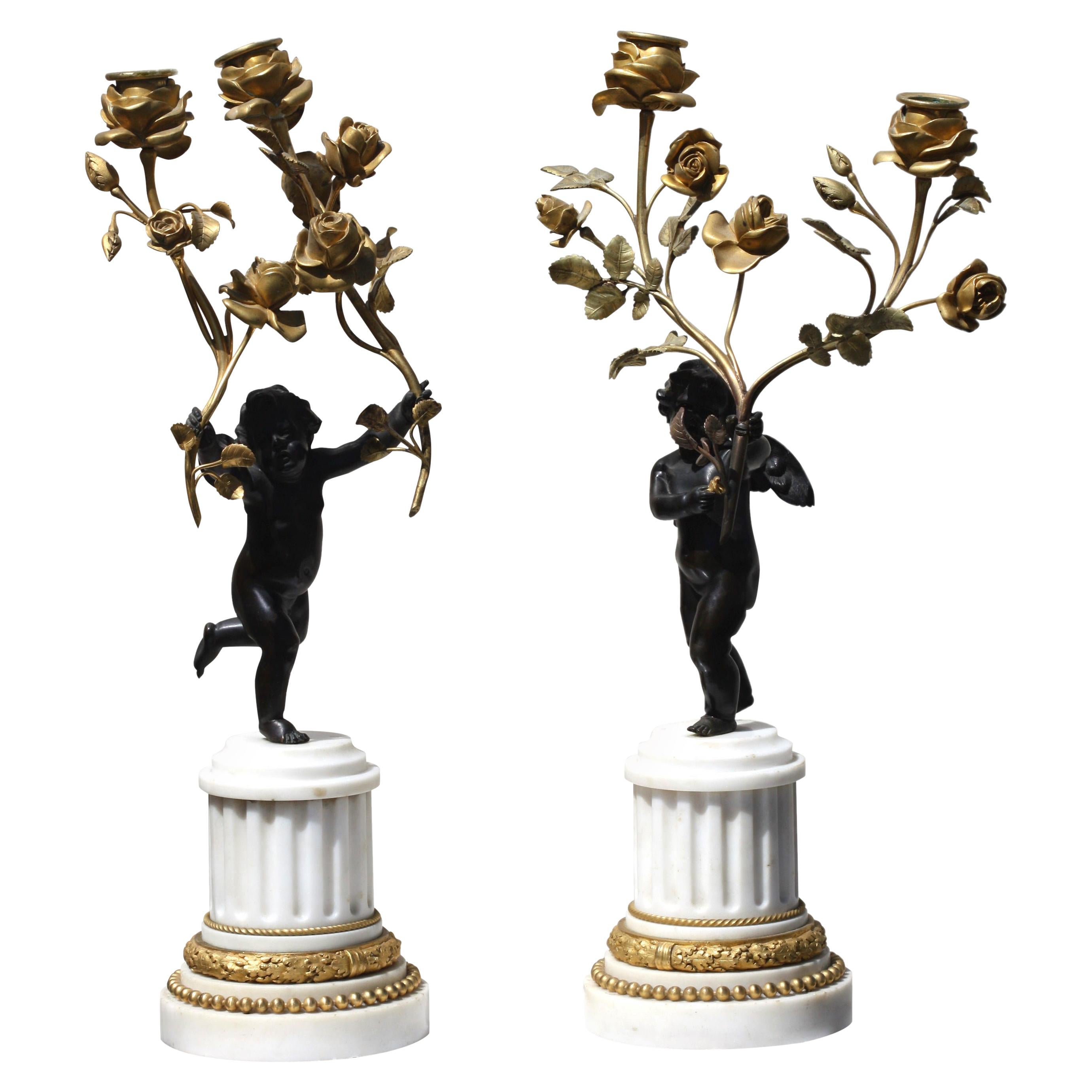 Paire de candélabres figuratifs de chérubin debout en bronze patiné et bronze doré