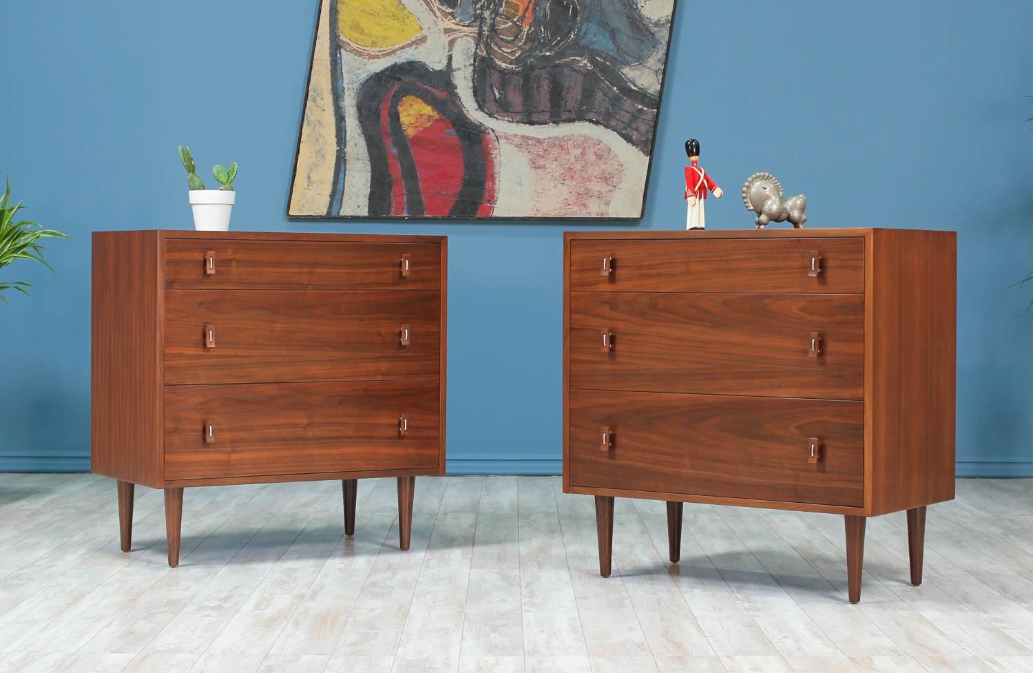 A beautiful pair of chests designed by Stanley Young for Glenn of California in the United States circa 1950’s. Each chest features a walnut wood case with three dovetailed drawers accented with Young’s signature bentwood and steel pulls sitting on