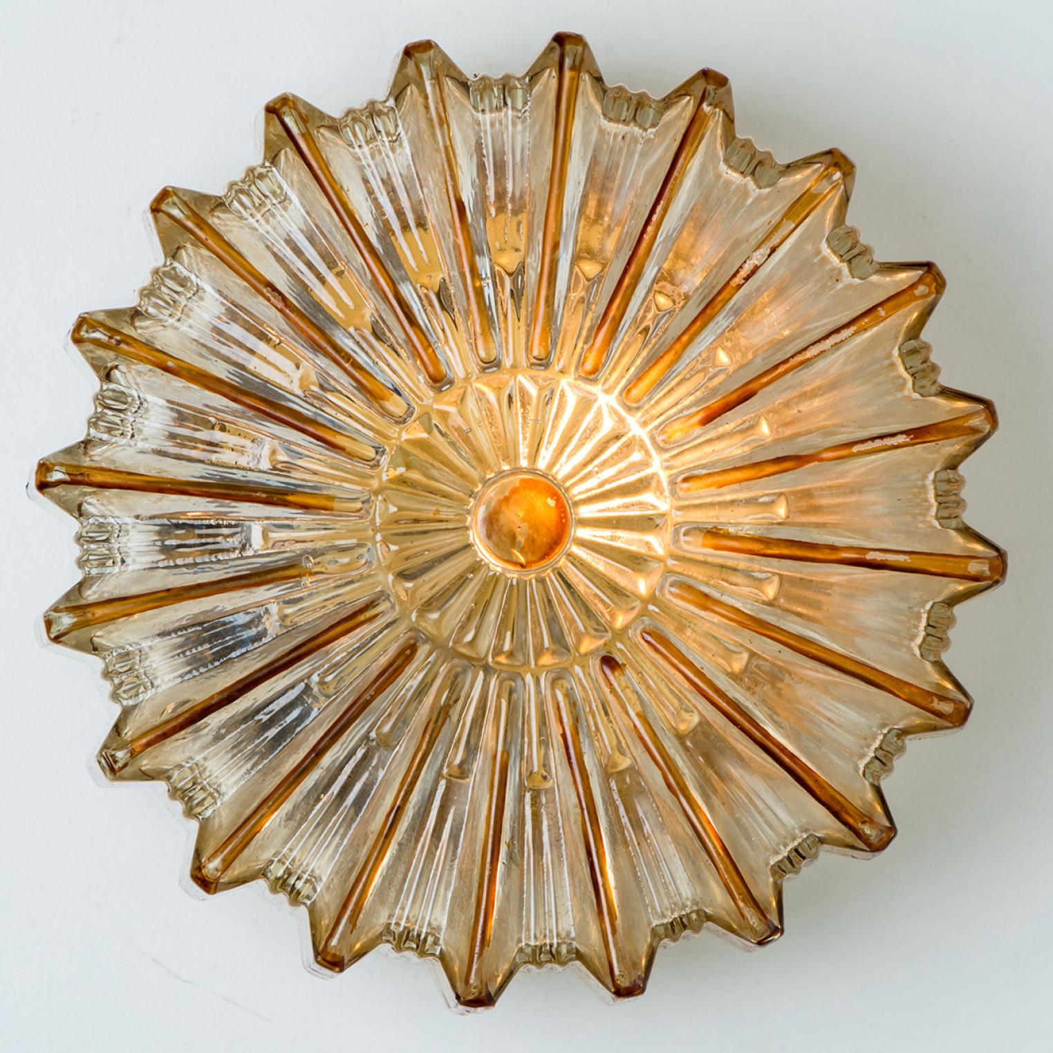 Pair of Clear and amber colored bubble glass wall light designed in the style of Helena Tynell around 1960-1970 in Europe, Germany. The rich textured bubbled glass gives a wonderful glow. The star-shaped glass is mounted on a gold colored metal back