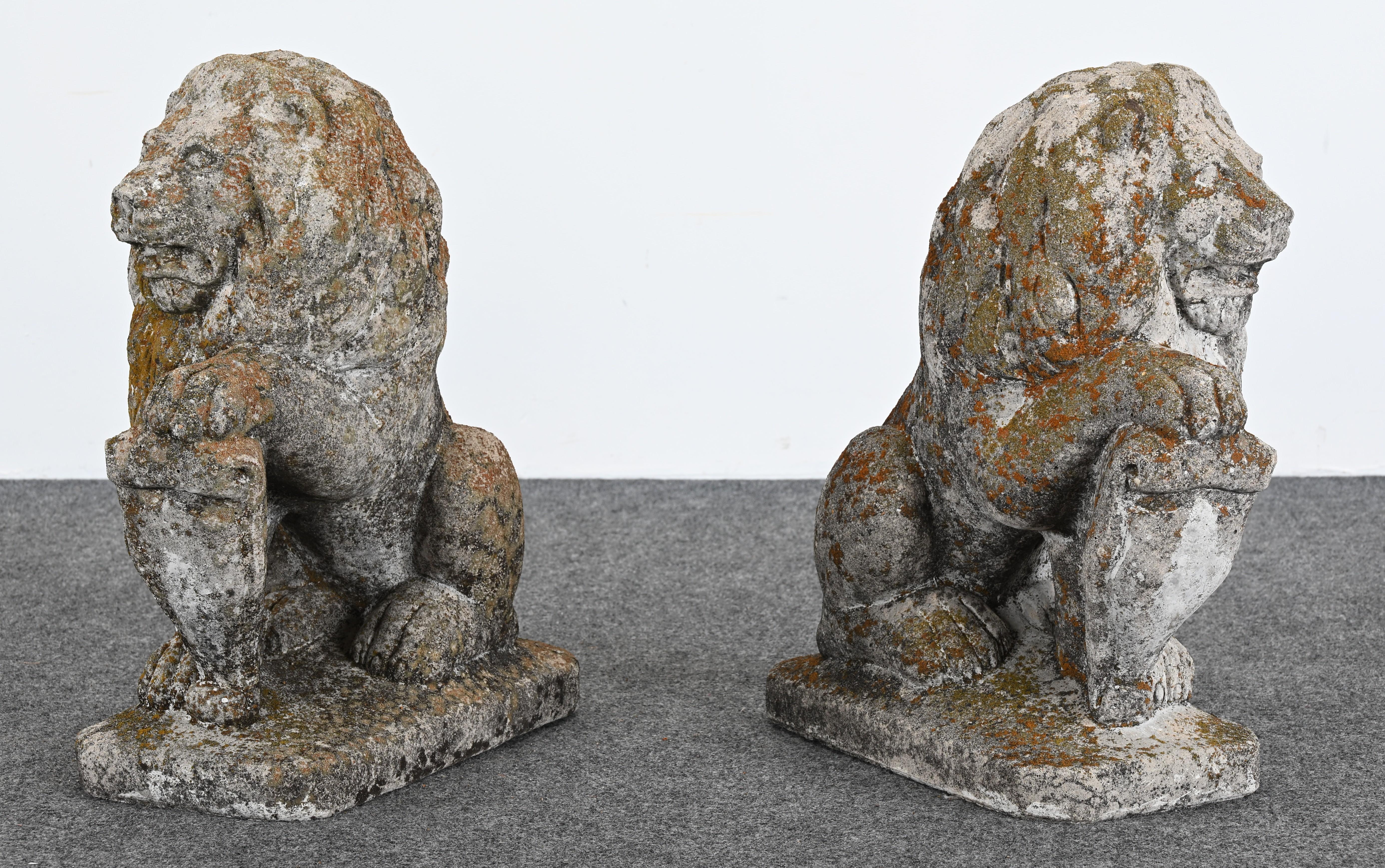 A pair of stately, solid cast stone lions circa 1960 from a prestigious Pennsylvania estate.  The seated lions exude strength, perfect for elevating an outdoor space. The gorgeous patina and weathered surface, with moss and lichen, emulate years of