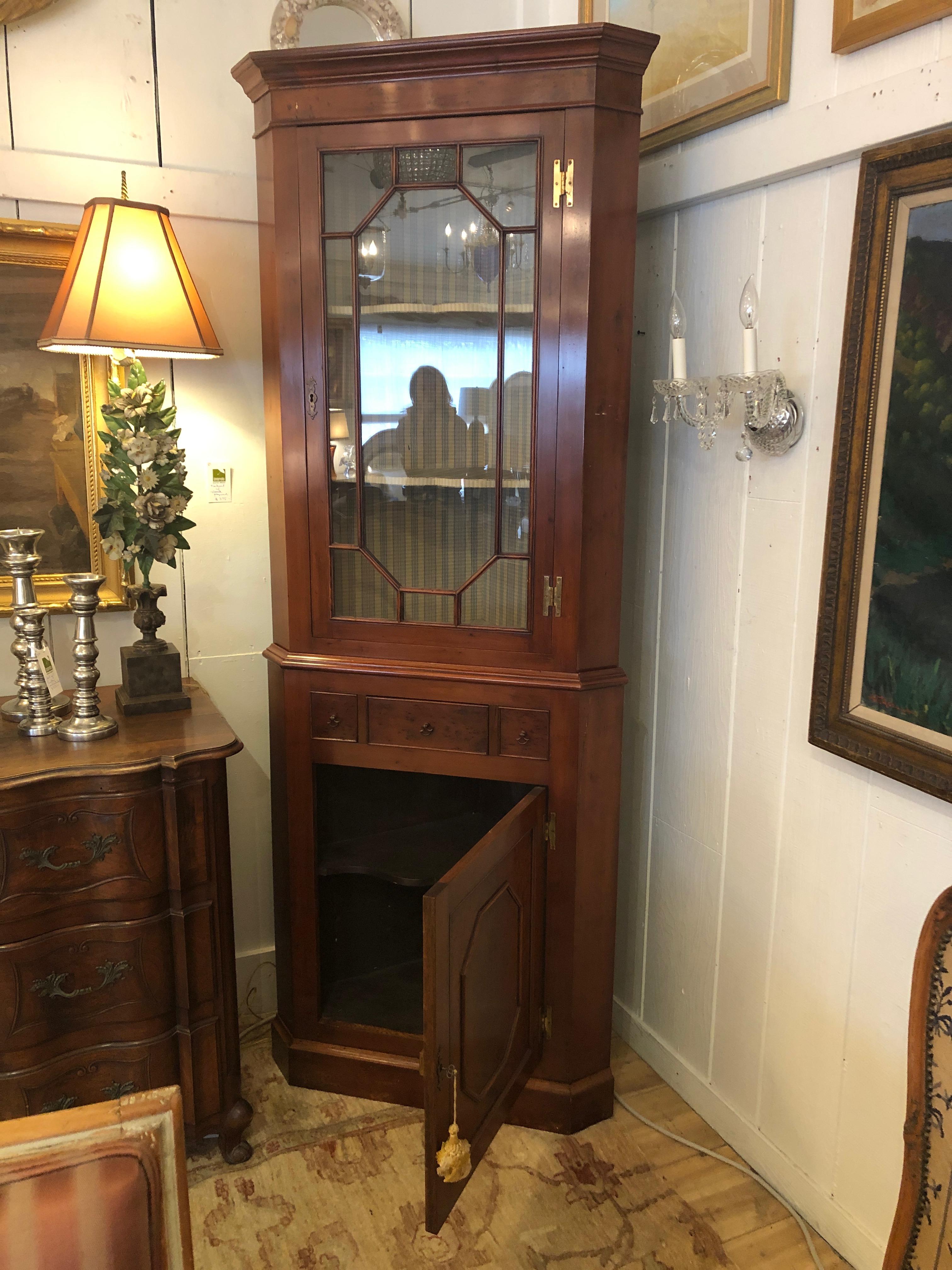 Two stunning mahogany Chippendale style corner cabinets having glass doors on upper half with beautiful designed mullions, simple crests at the top with sophisticated lines, a single drawer and paneled door below with storage inside. Interior of the