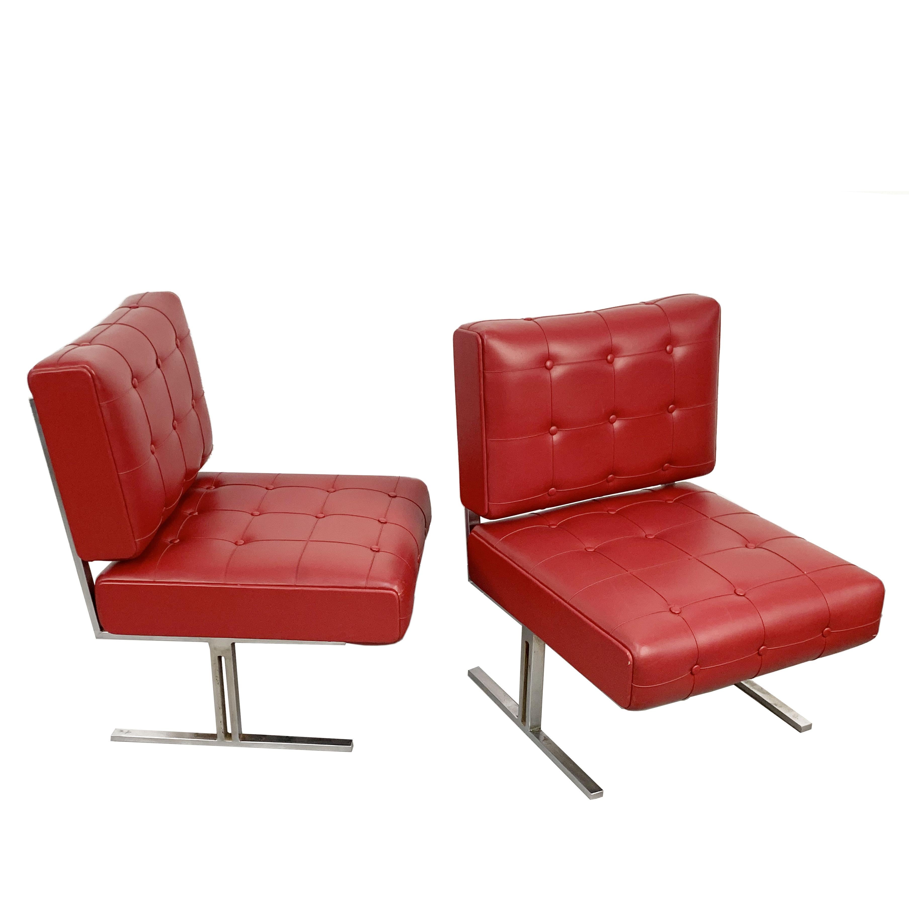 Rare red vintage leatherette lounge chairs in the style of Robert Haussmann for De Sede. 

Hand-built in Italy during the 1950s, these rare armchairs have a chromed steel frame and red faux leather, capitonne, cushions.

The conditions are
