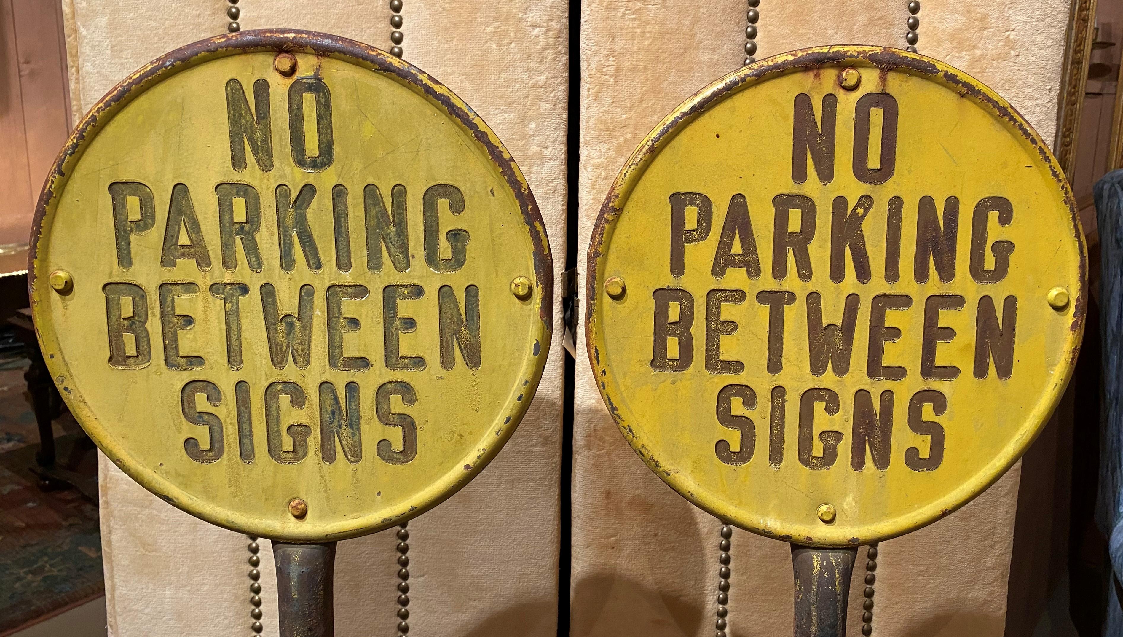 A fine pair of circular yellow painted steel signs which read “No Parking Between Signs,” with cast iron poles and round bases, embossed “Lyle Signs, Minneapolis”. These street signs date to the 1930’s and are in very good condition, with some