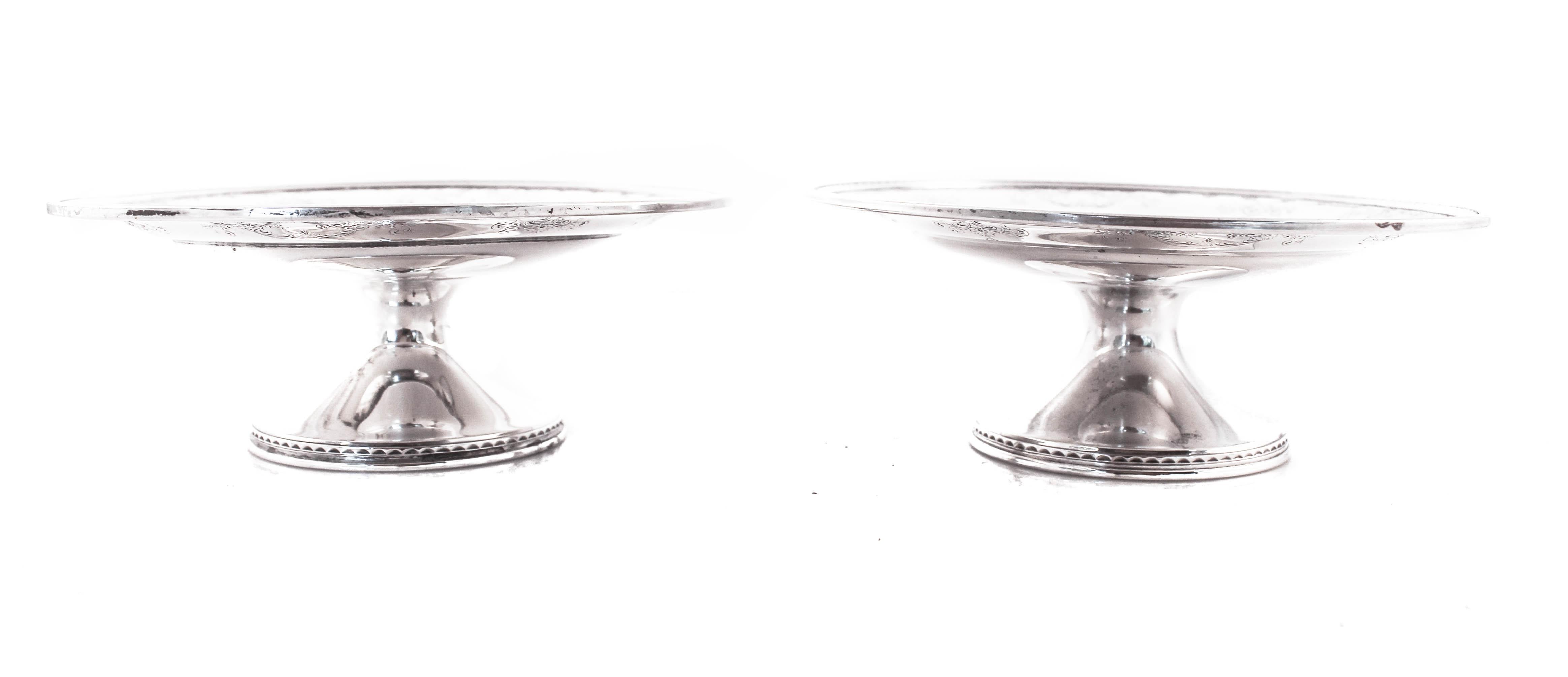 We are delighted to offer this pair of sterling silver compotes by Dominick and Haff of New York City. They have old-world charm; garlands, bows and other decorative etchings grace the other edge of each compote. In the center a hand engraved script