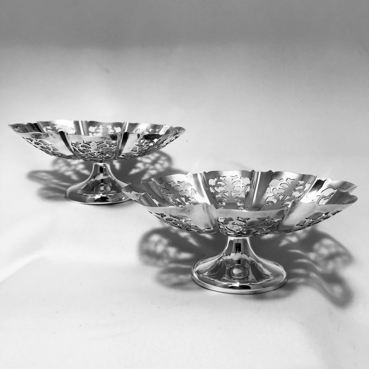 A pair of hall marked sterling silver Tazzae, each bowl of scalloped circular form, profusely pierced with stylized acanthus, raised on a circular foot marked for Sheffield 1933 by Edward Viner.

This sort of cutwork went out of fashion in the