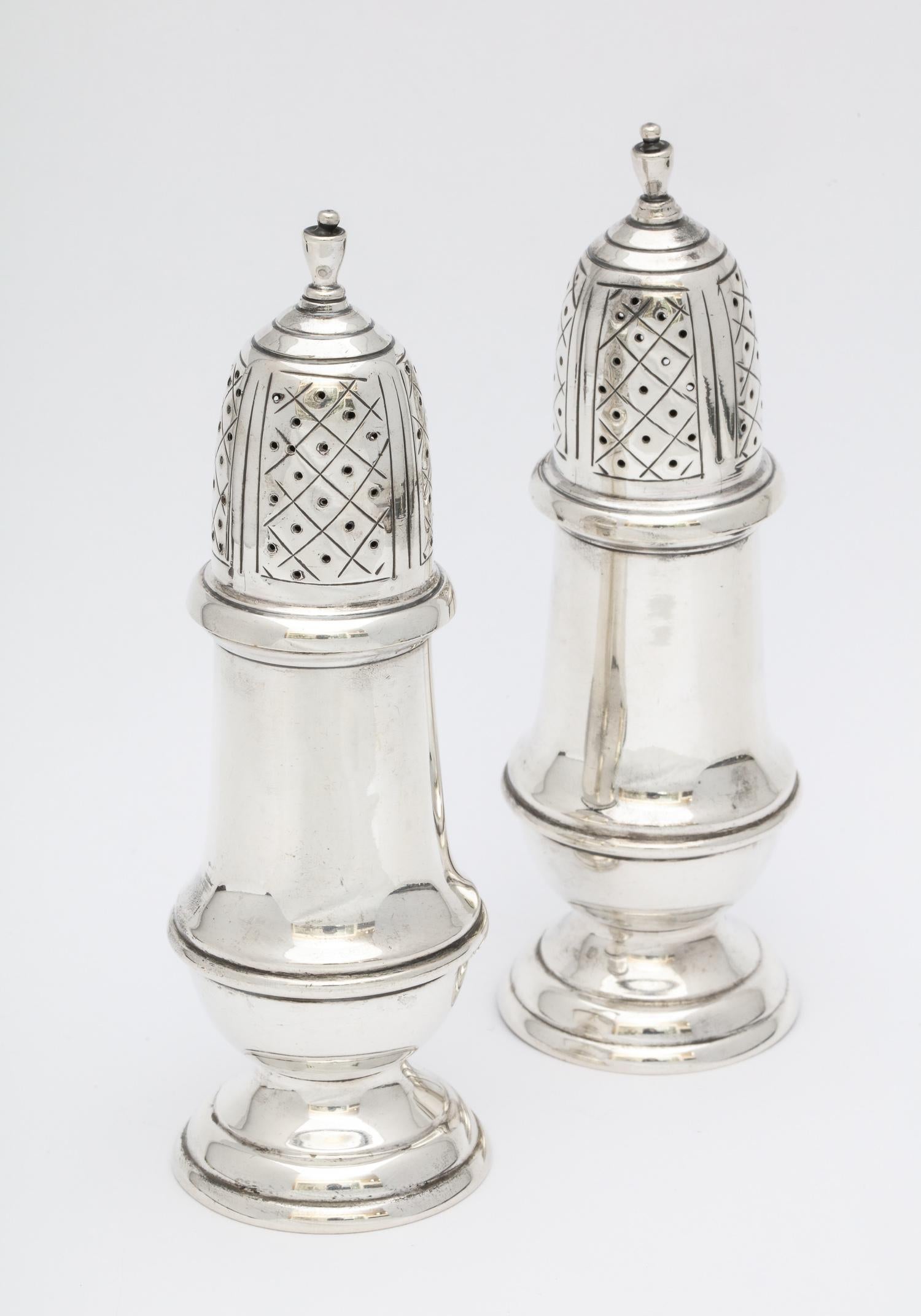 Pair of sterling silver, American Colonial style salt and pepper shakers or casters, American, circa 1930s. Made as reproductions of a pair made by Benjamin Burt (1729-1804). Each measures 5 3/4 inches high x 1 3/4 inches diameter at widest point;