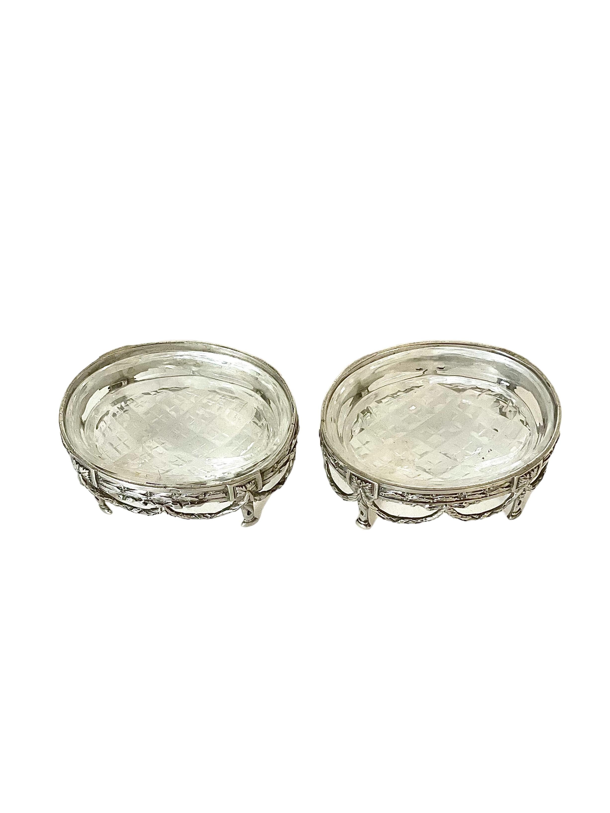 An exquisite pair of Louis XVI-style cauldron-shaped, sterling silver salt cellars, finely decorated with swags and motifs of asparagus and laurel wreaths. 
Dating from around the turn of the 20th century, these feature removable white crystal