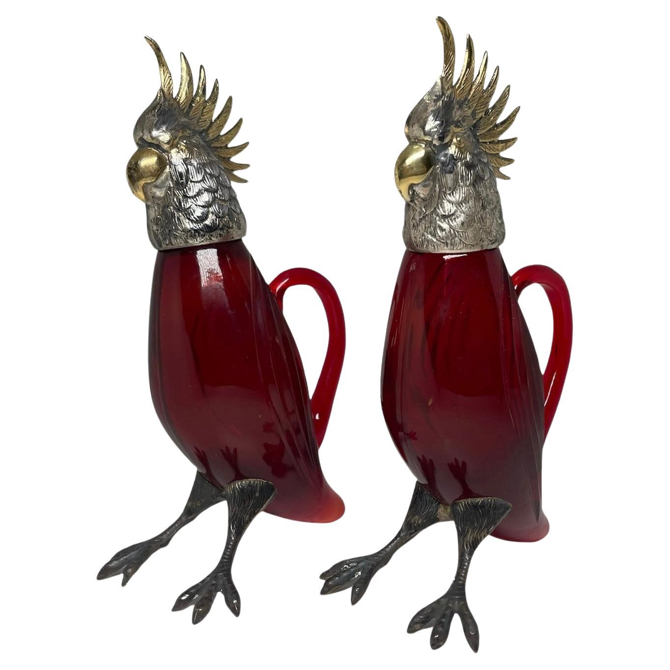 This is a Pair of Sterling Silver And Glass Cockatiel Cruet for storage of oil and vinegar. It depicts a pair of Cockatiel sculptures in which  their bodies are made of ruby red glass and their heads and feet are made of sterling silver. Their