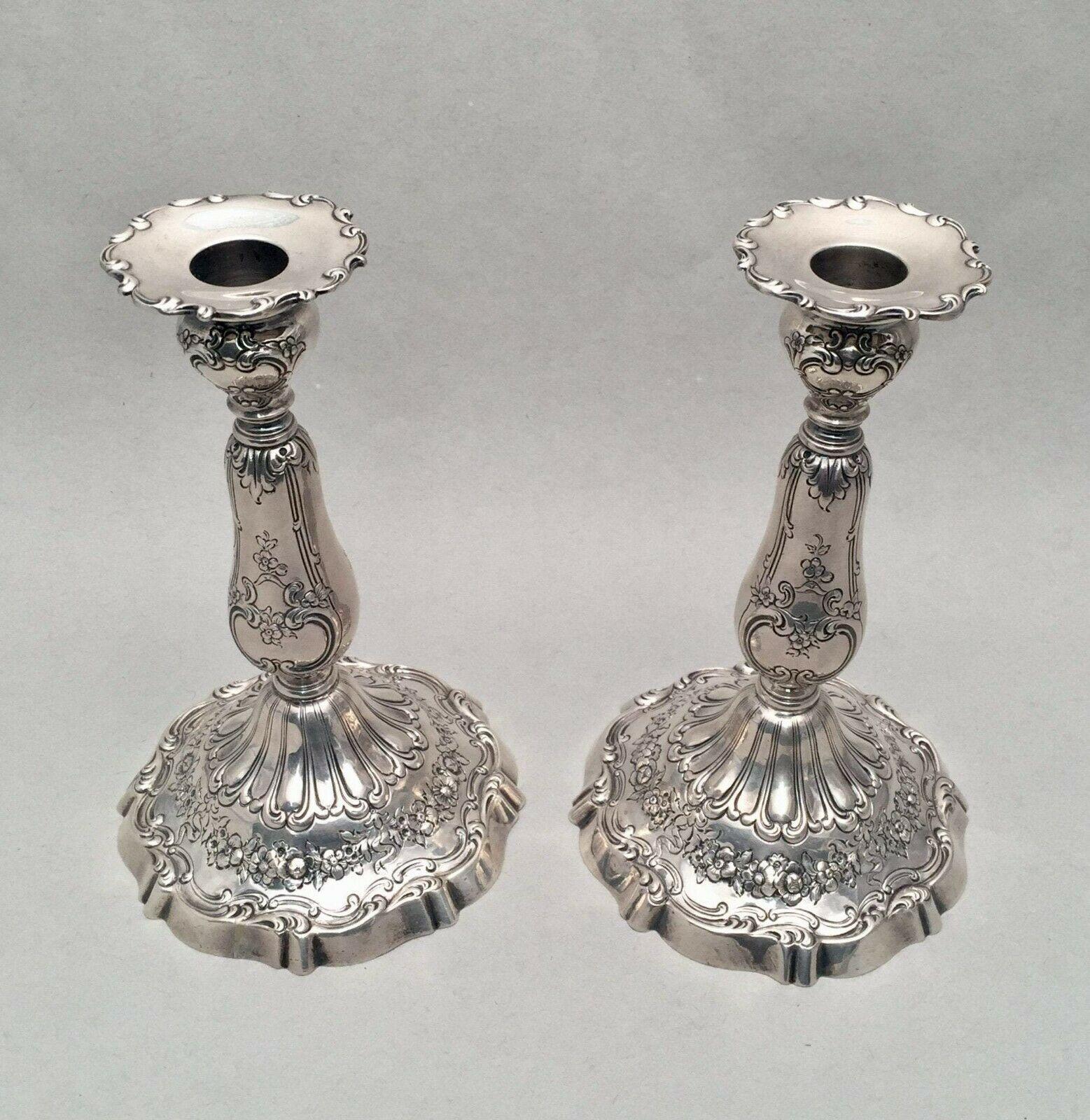 Pair of beautiful of sterling silver candlesticks / Shabbos candlesticks by American maker Reed & Barton. Designed with enamoring flowers and scrolls. Border of bobeche designed in scroll pattern. Measuring 8 inches tall and 5 inches wide at base.