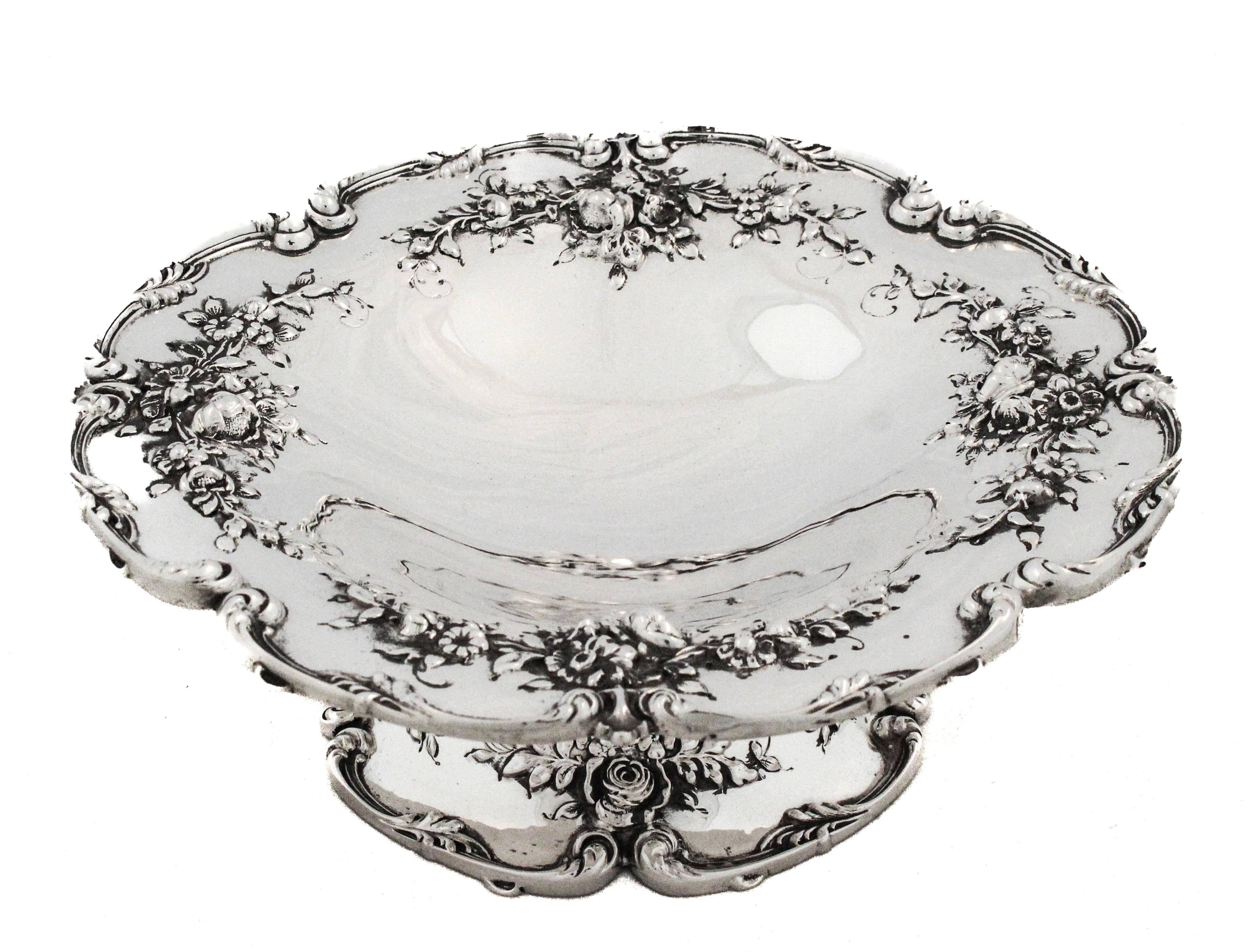 Un'impressionante coppia di composte in argento sterling prodotte da Redlich & Company, che misurano 9 pollici di larghezza per 3 pollici di altezza. Ogni pezzo presenta un bordo graziosamente smerlato ornato da quattro grappoli di fiori finemente