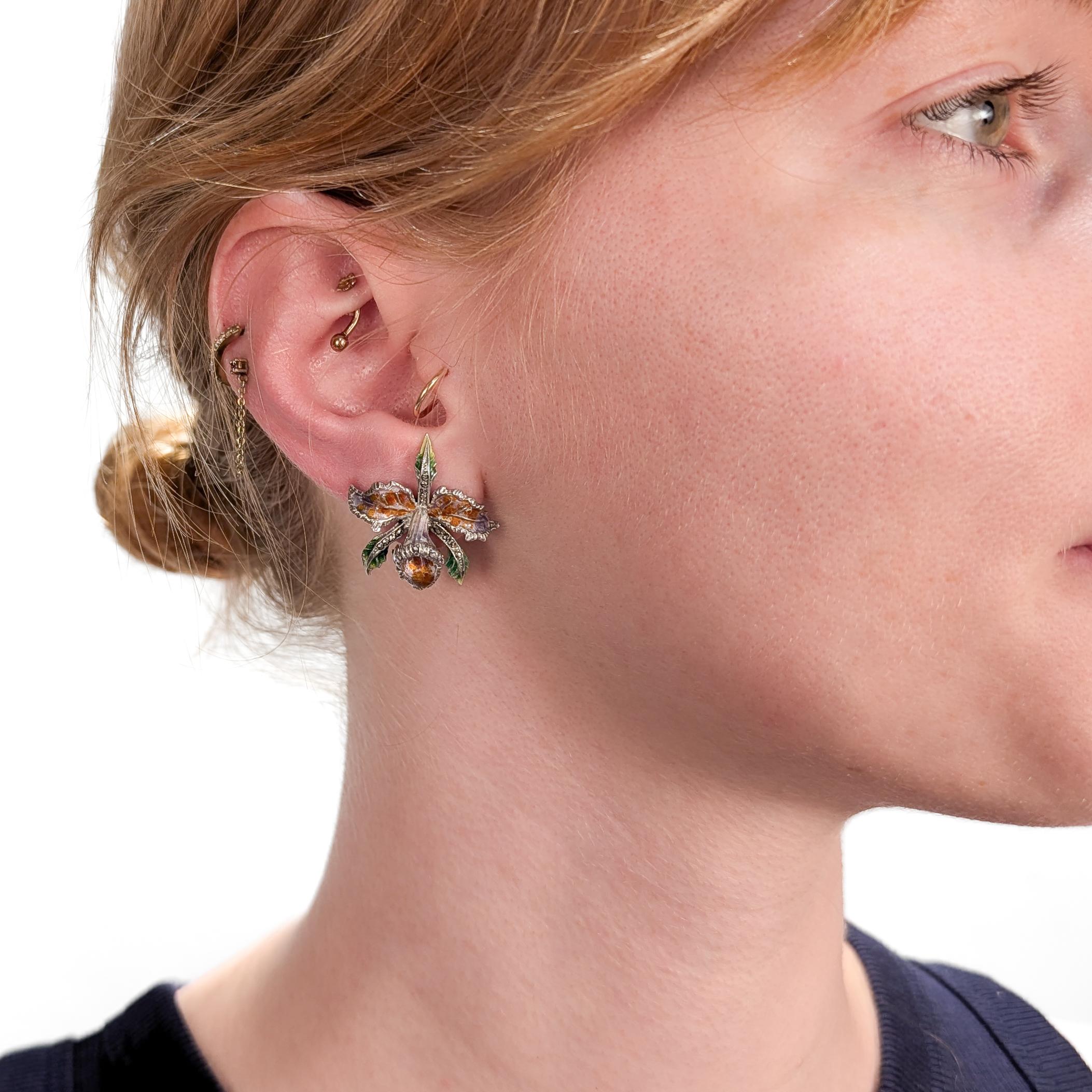 A fine vintage pair of silver, marcasite, and enamel earrings.

In sterling silver.

Each in the form of a cattleya orchid with enameled petals and marcasite accents.

Secured with ear clips to the reverse of each. 

Marked to the the reverse and to