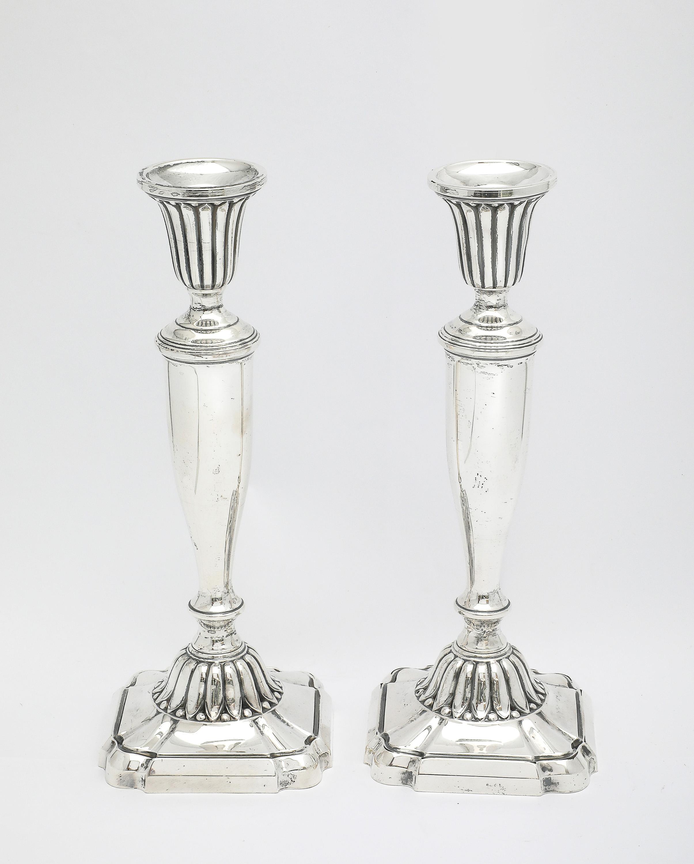 Pair of sterling silver, Neoclassical-Style candlesticks, The Mueck-Carey Co., New York, Ca 1940. Each candlestick measures 9 inches high x 3 1/2 inches wide (at widest point - across scalloped edge of base) x 3 1/2 inches deep (at deepest point -