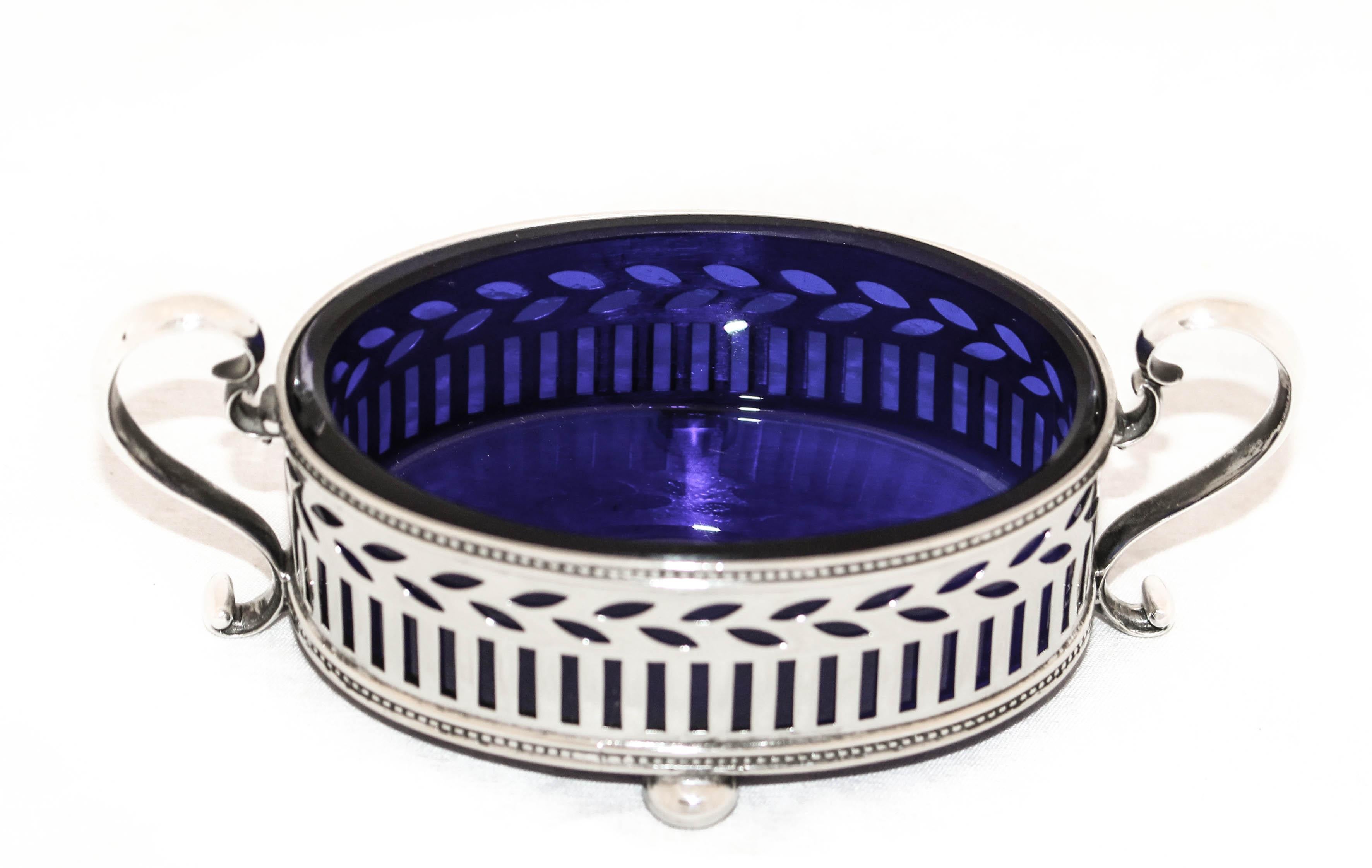 Being offered is a pair of antique sterling silver master salt cellars by the world renowned Tiffany & Company.  They have cobalt liners and a reticulated design that allows the deep blue glass to shine through.  There are swirl style handles on