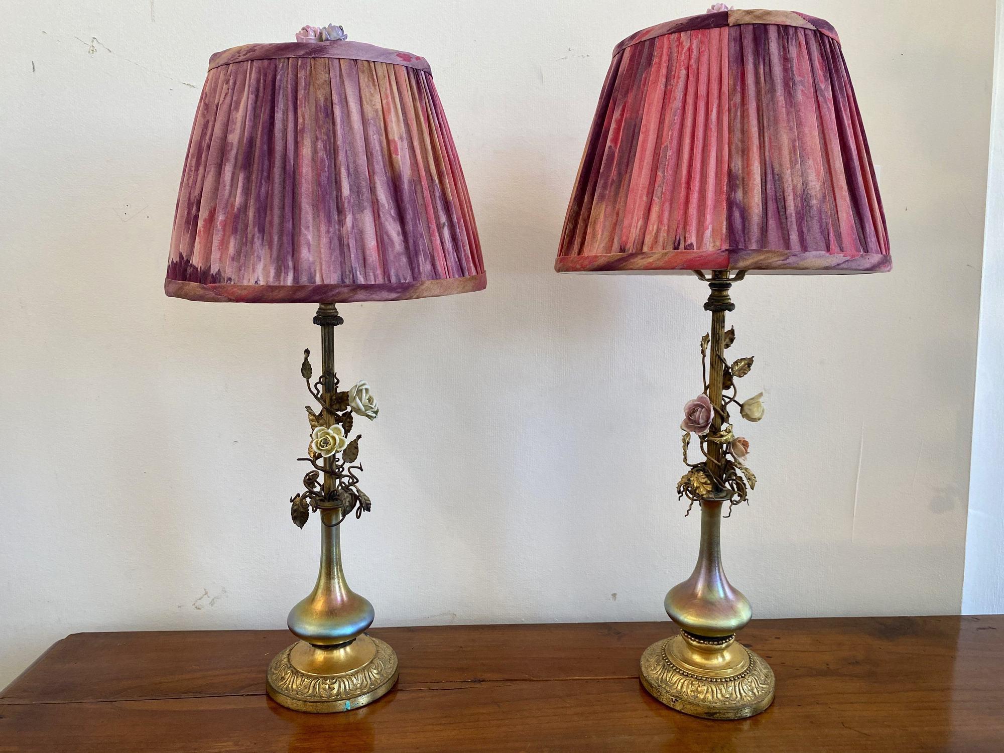 Near pair of Steuben Aurene Glass Vases converted to lamps with brass bases and stems, adorned with ormolu leaves and vines and porcelain roses. Finials are also porcelain roses. The shades are custom, hand-dyed silk. 23” h. to the top of the