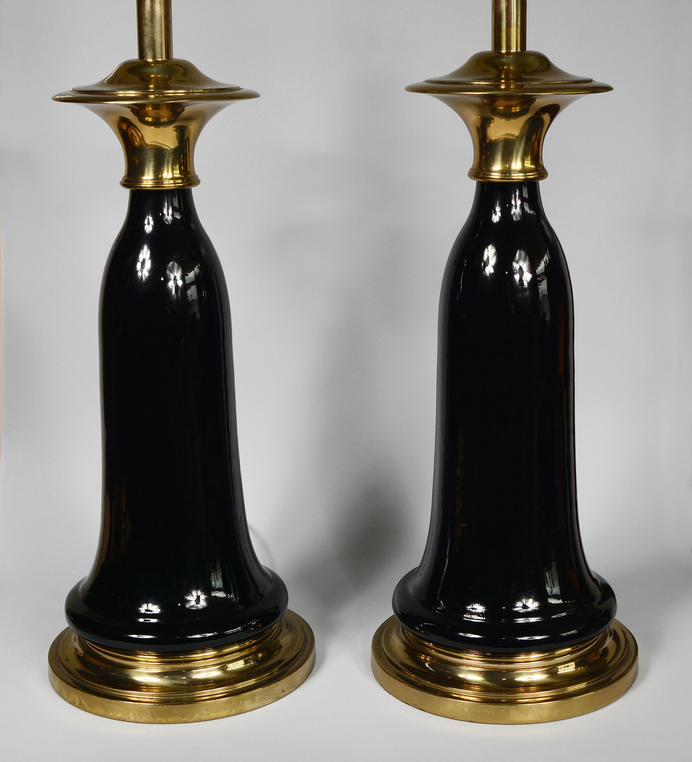 Pair of tassel form lamps by Stiffel. The have ceramic bodies with a high gloss black glaze with brass bases and a flaring brass top. The lamps are in very good condition. There are a few areas of oxidation to the brass. The finials are