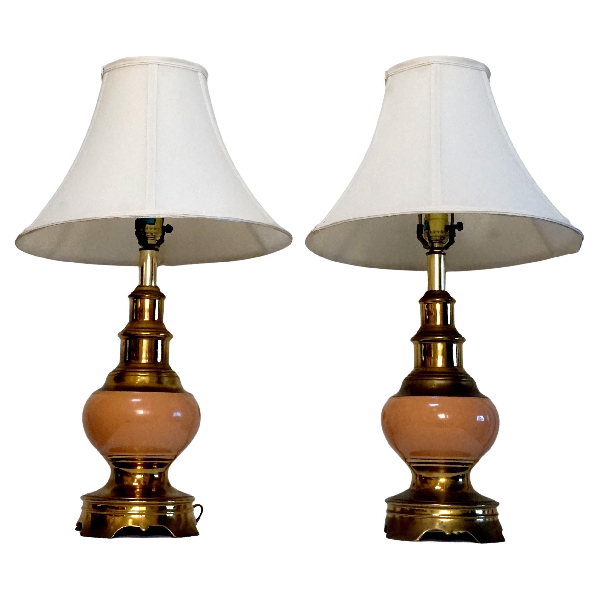A pair of vintage Stiffel brass and ceramic table lamps steal the scene in a high glaze coral accented with brass. The pair is in wonderful vintage condition and presents well.
 The brass finish has developed a deeper patina over time -- no brassy