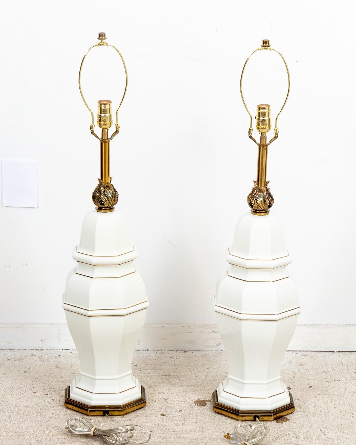 Pair of Regency style brass and white ceramic Stiffel lamps with thin gold band. Cast flame detail. In good working condition. Please note of wear consistent with age. Rewired. Shades not included.